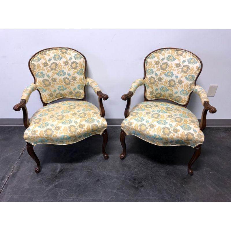 A pair of vintage French Provincial Louis XV Style fauteuils open armchairs, unbranded. Carved walnut frame with fabric upholstery of cream, golds, blues and greys. Made in the USA, in the late 20th Century.

Measures:  Overall: 26W 26D 35H, Seats: