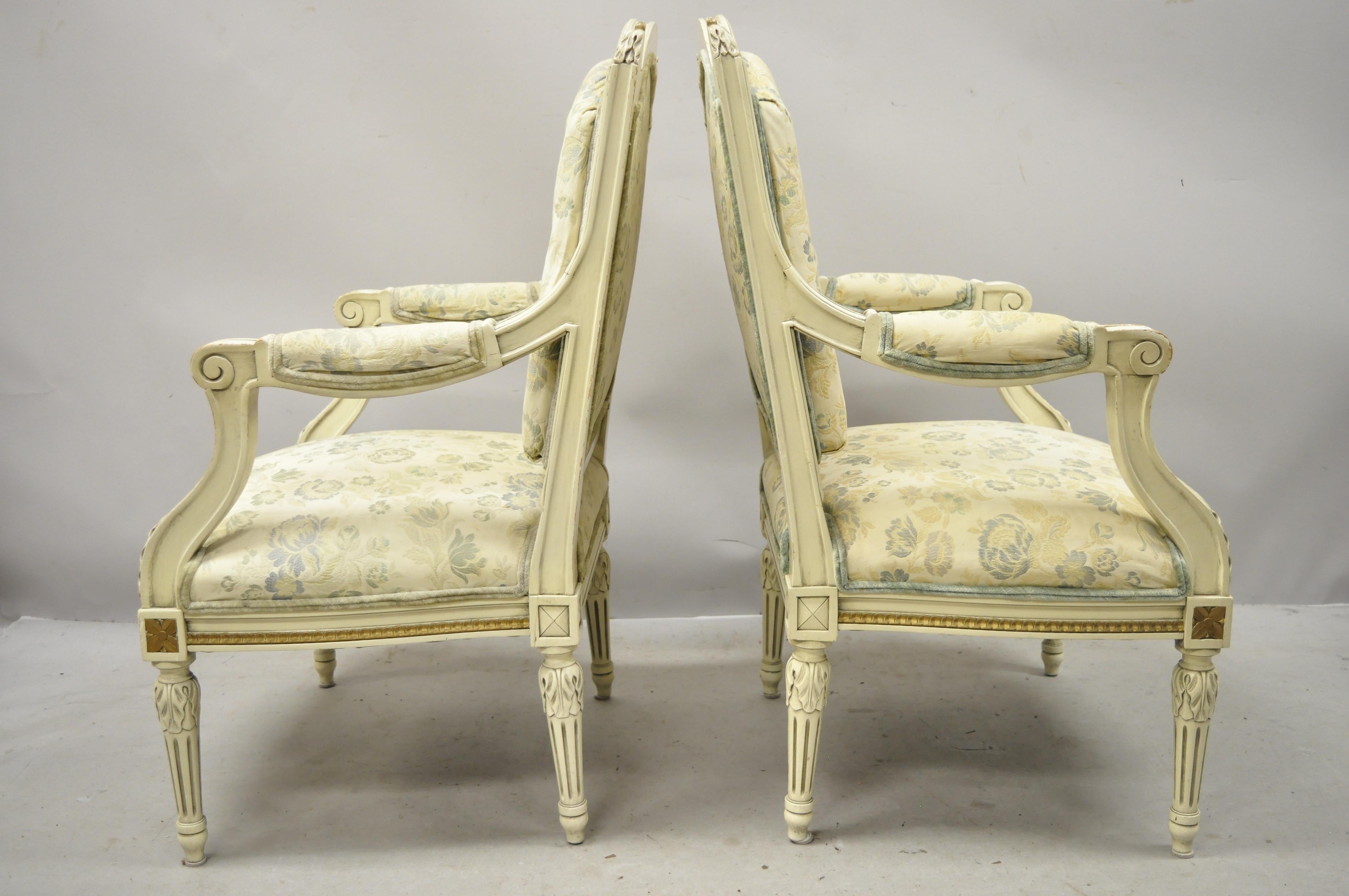 Vintage French Provincial Louis XVI style cream painted Fauteuil armchairs - a pair. Item features solid wood frame, upholstered arm rests, distressed finish, nicely carved details, tapered legs, great style and form, circa mid-20th century.