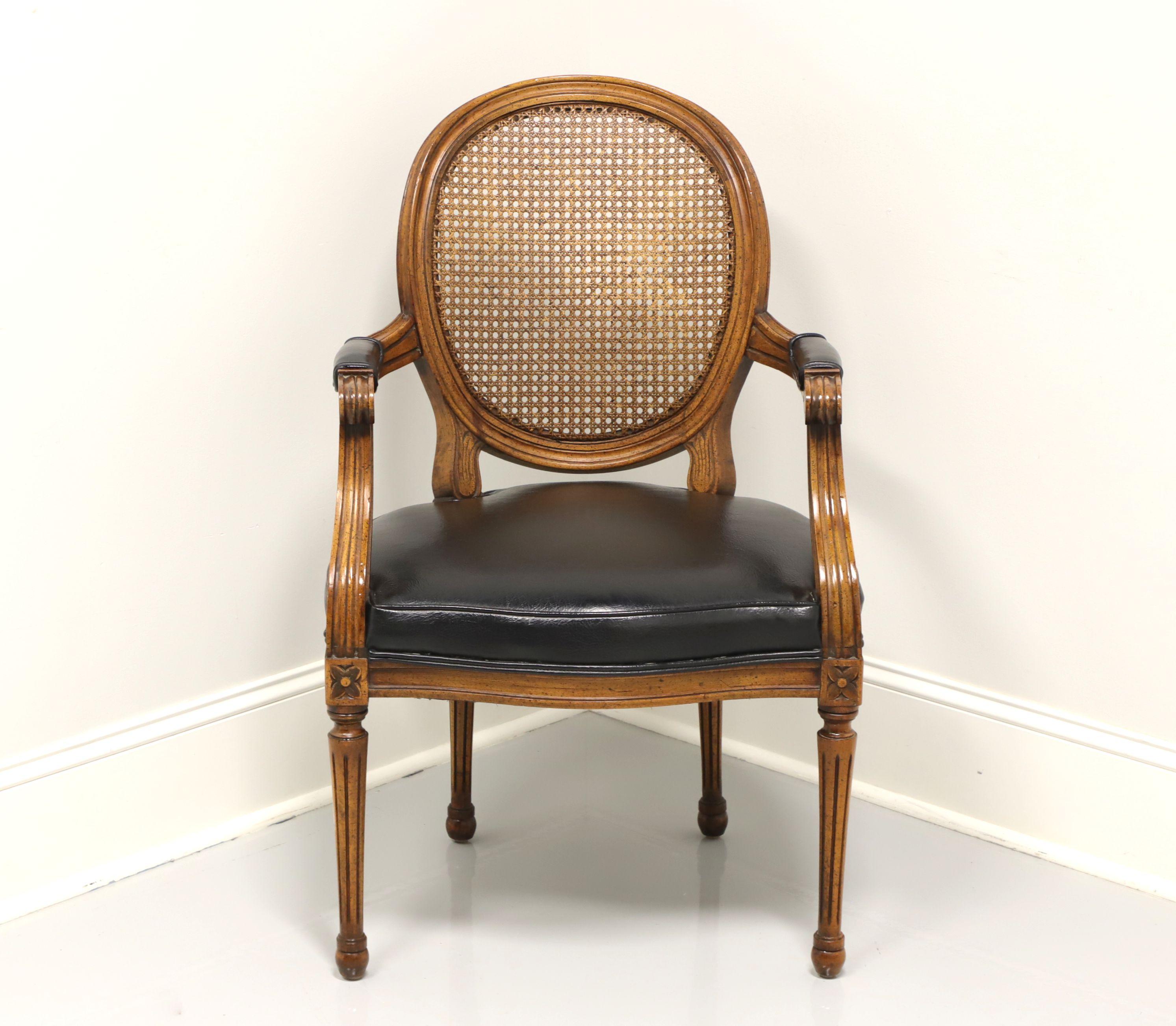 A French Provincial Louis XVI style armchair, unbranded, similar in quality to Henredon. Walnut with caned oval back, curved arms with black leather armrests, black leather upholstered seat, block carved knees, turned and fluted legs. Made in the