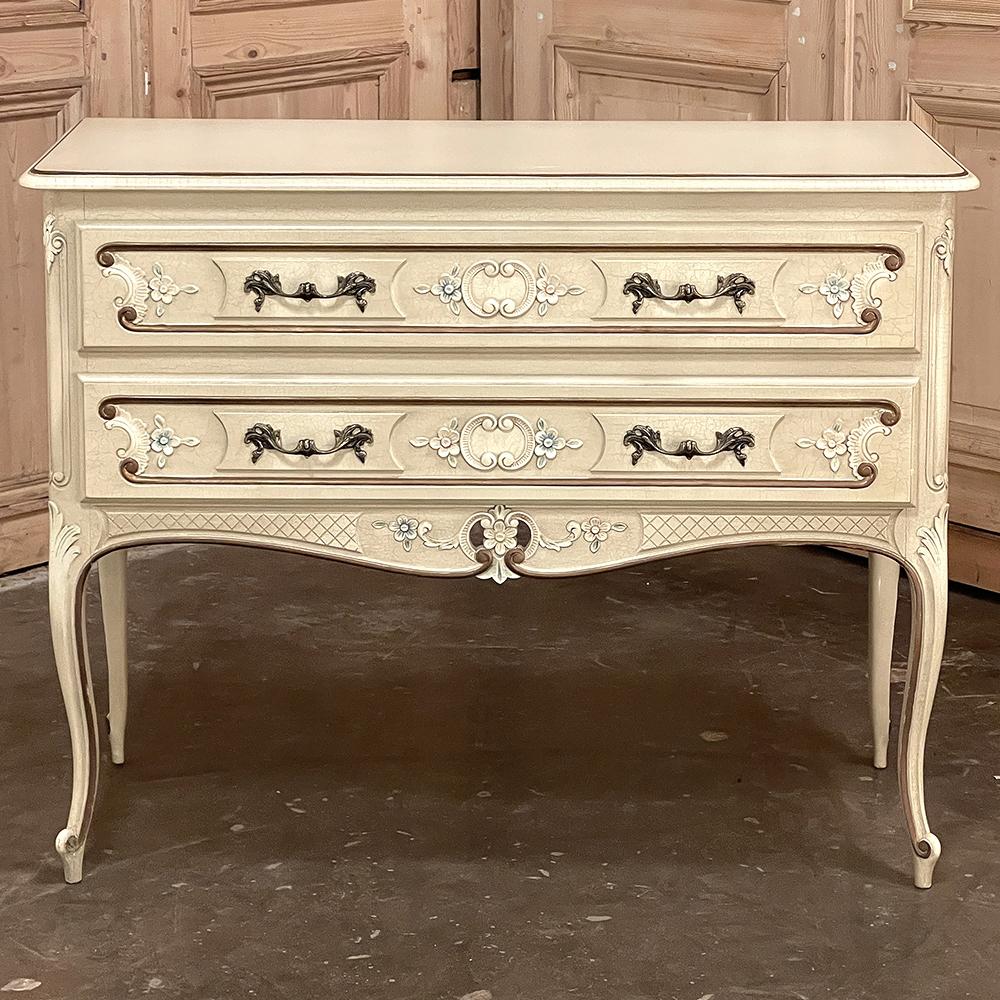 Cette commode provinciale française peinte fera un ajout charmant à n'importe quelle pièce ! La finition peinte ivoire/beige a acquis une belle patine, et est soulignée par des accents dorés sur les détails moulés qui encadrent la paire de tiroirs,