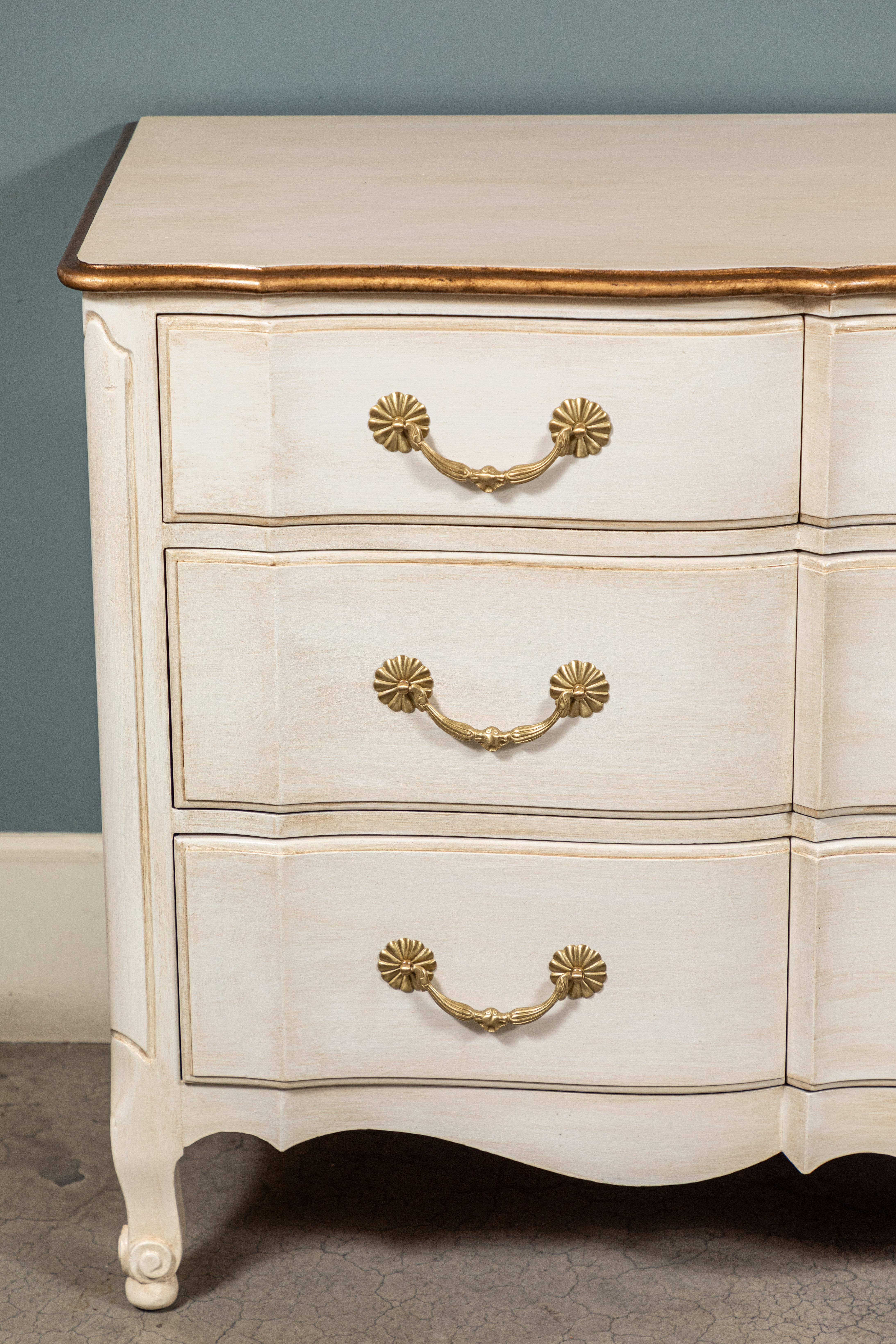 Vintage French Provincial style walnut dresser with 9 drawers that has been newly refinished and hand-painted in a creamy white with gold trim detail.

The brass hardware has been polished in a satin finish.
