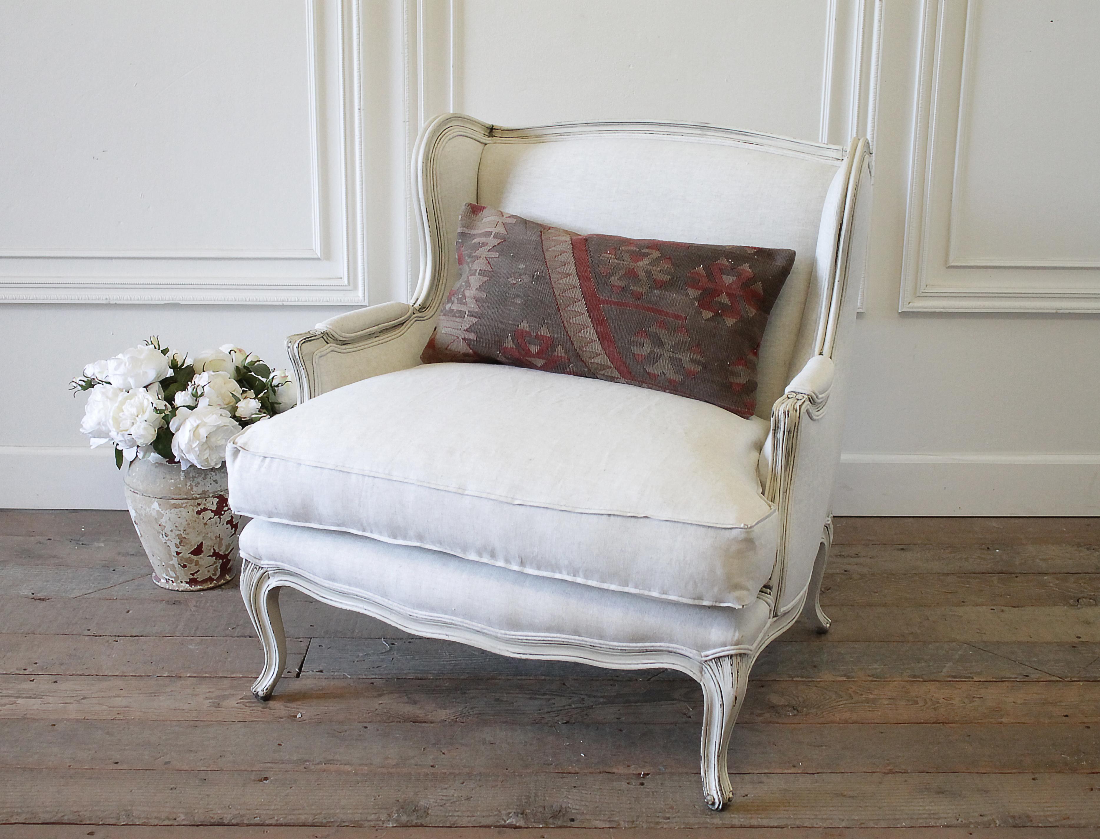 Vintage French Provincial wing back style chair upholstered in natural linen
Painted in our oyster white, which is an off white with subtle distressed edges, and antique glazed patina. Legs are solid and sturdy, cushion is down wrapped, medium-firm