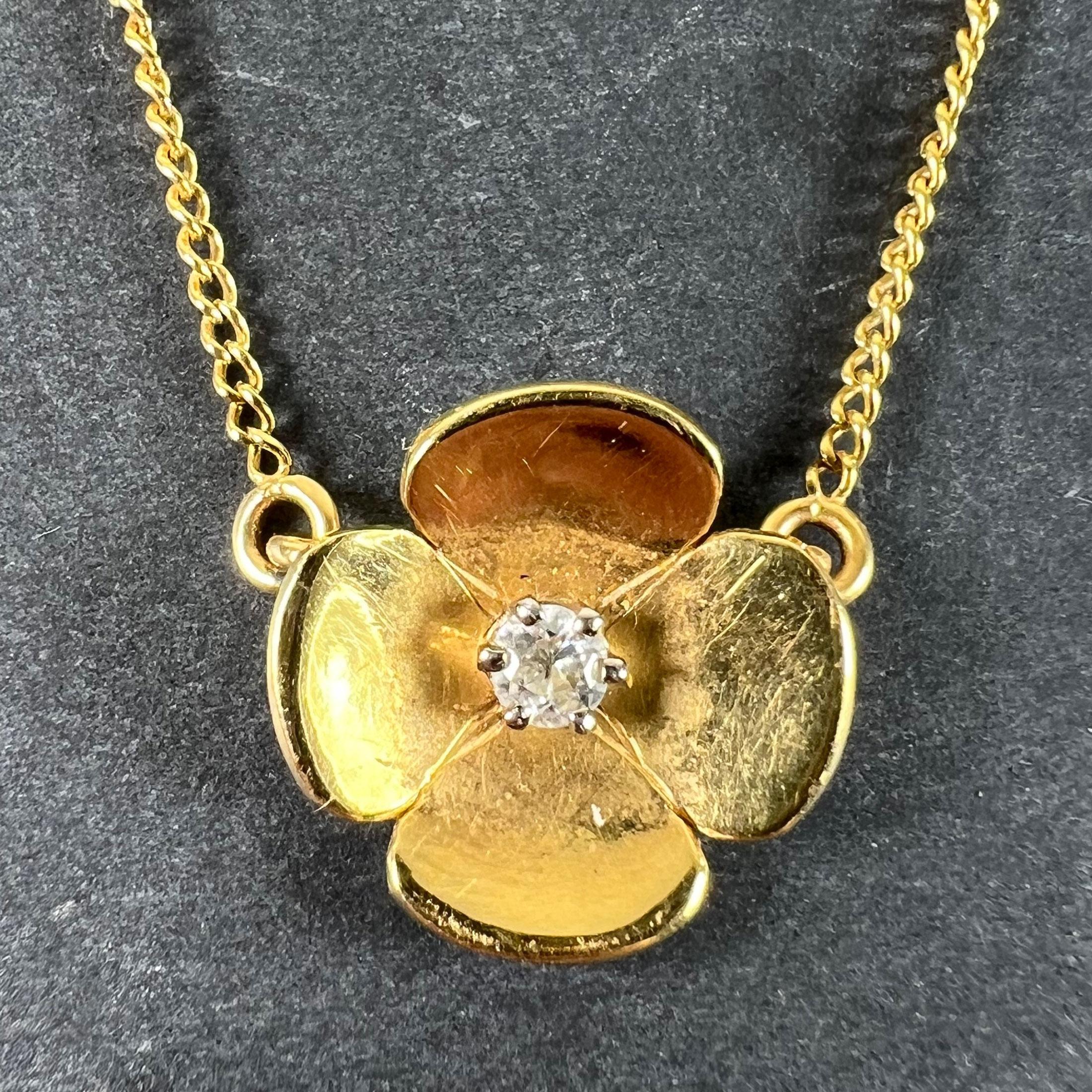 Un collier vintage français en or jaune 18 carats (18K) avec un pendentif attaché conçu comme une fleur quadrilobée avec quatre pétales, centré avec un diamant de taille ancienne européenne pesant environ 0,25 carats, estimé comme étant de couleur