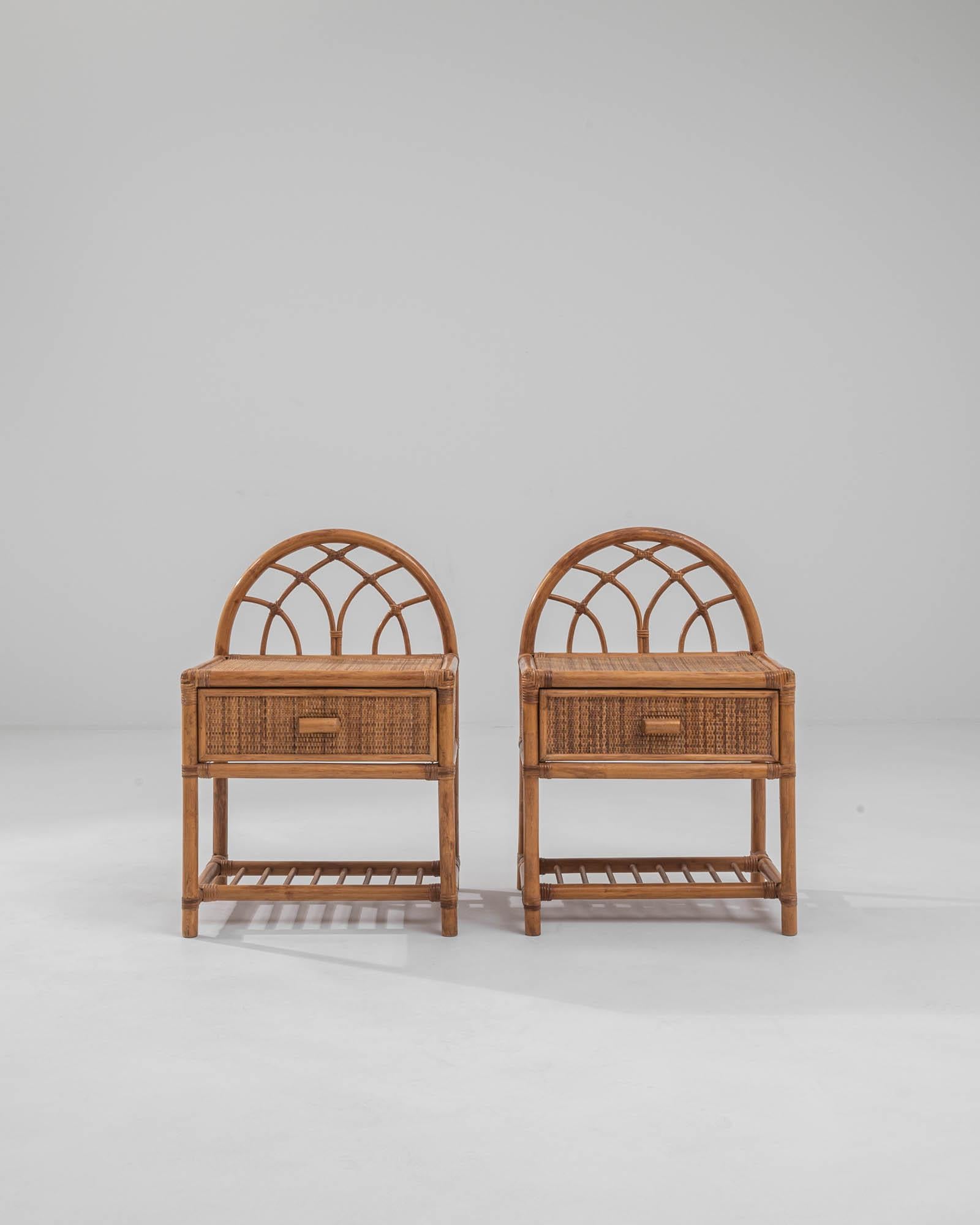A pair of bedside tables made in France circa 1900. Curved rattan backs, interwoven with smaller vines, compose a graceful backdrop to the flat woven wicker drawers that adorn these delightful tables. Hand-woven wicker and neatly tied lashings