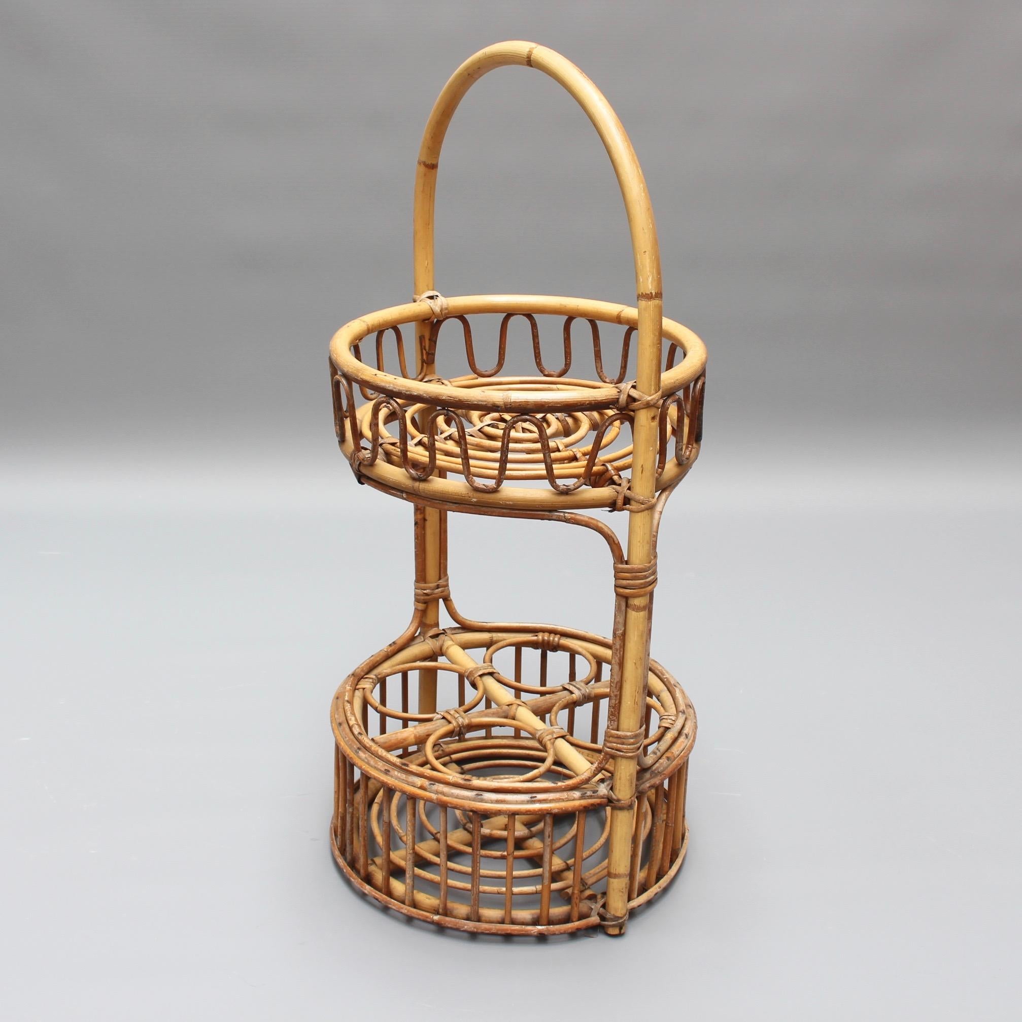 Vintage French rattan drinks rack, (circa 1960s). This is a charming piece with upper and lower horizontal surfaces with concentric circular rattan design held in place by two vertical canes. The lower level has four holding rings for your best