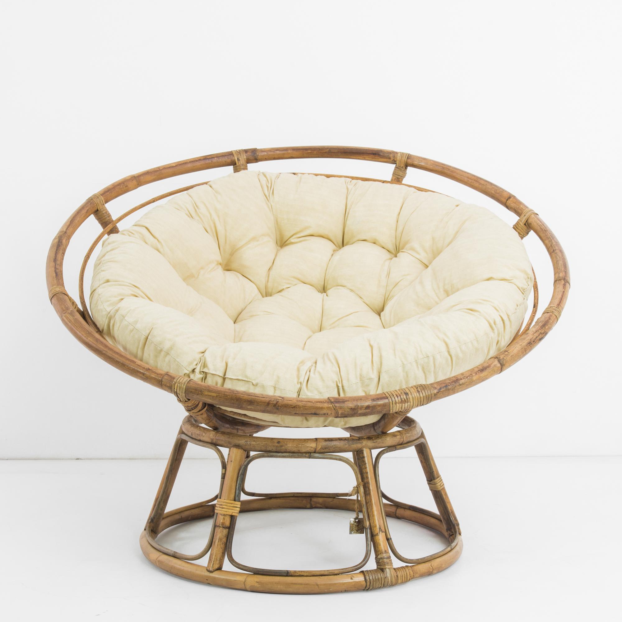 This papasan chair was made in France, circa 1980, and comes with a well-padded cream cushion for comfort and style. The bowl-shaped seat rests on a sturdy base. Handmade with rattan, weathered to a beautiful patina with a lived-in and cozy feel.
