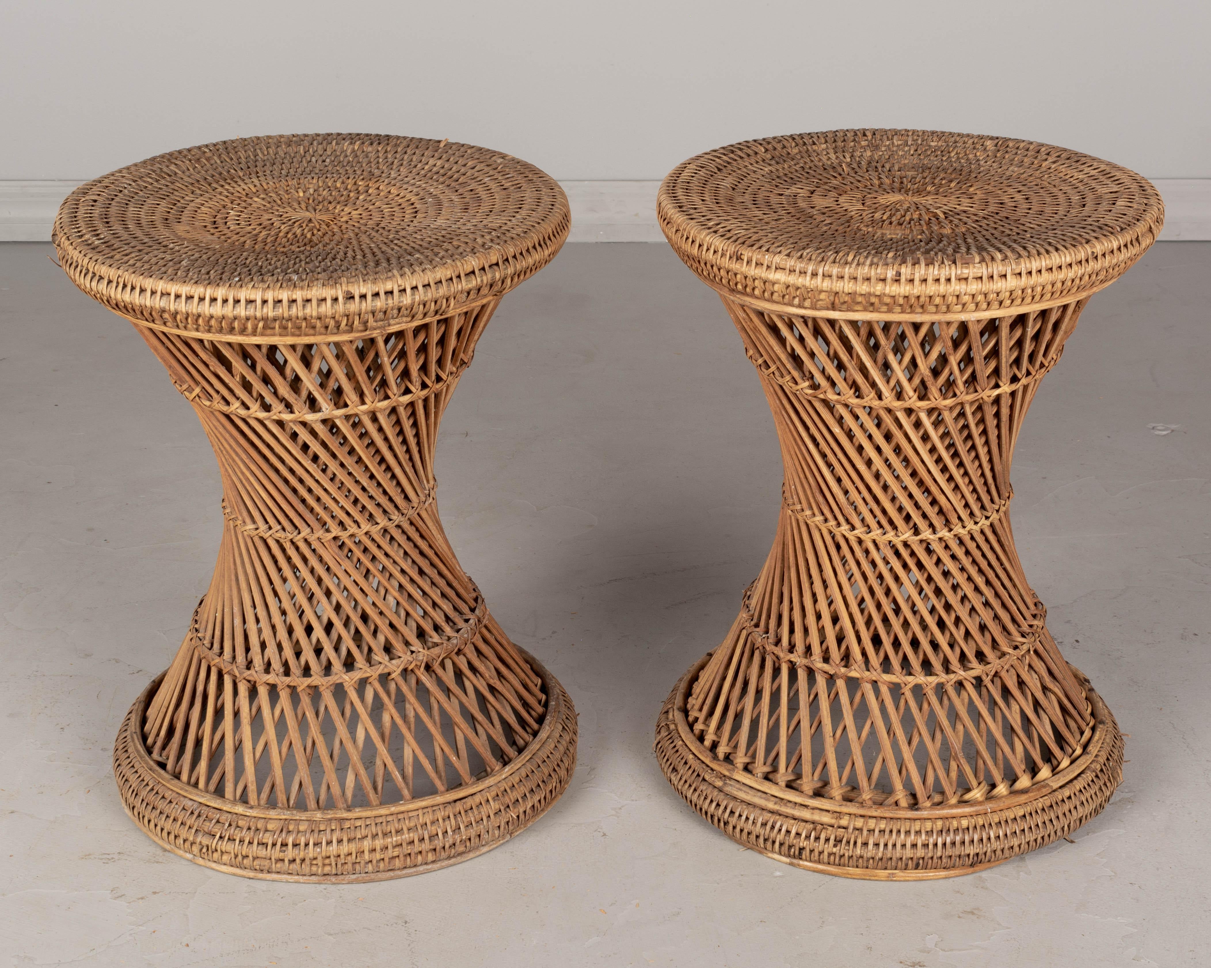 A pair of French mid century circular side tables made of hand woven rattan with handle on the side. Sturdy and in good condition. Minor losses. We have a large collection of rattan and bamboo furniture including a pair of peacock chairs.
   