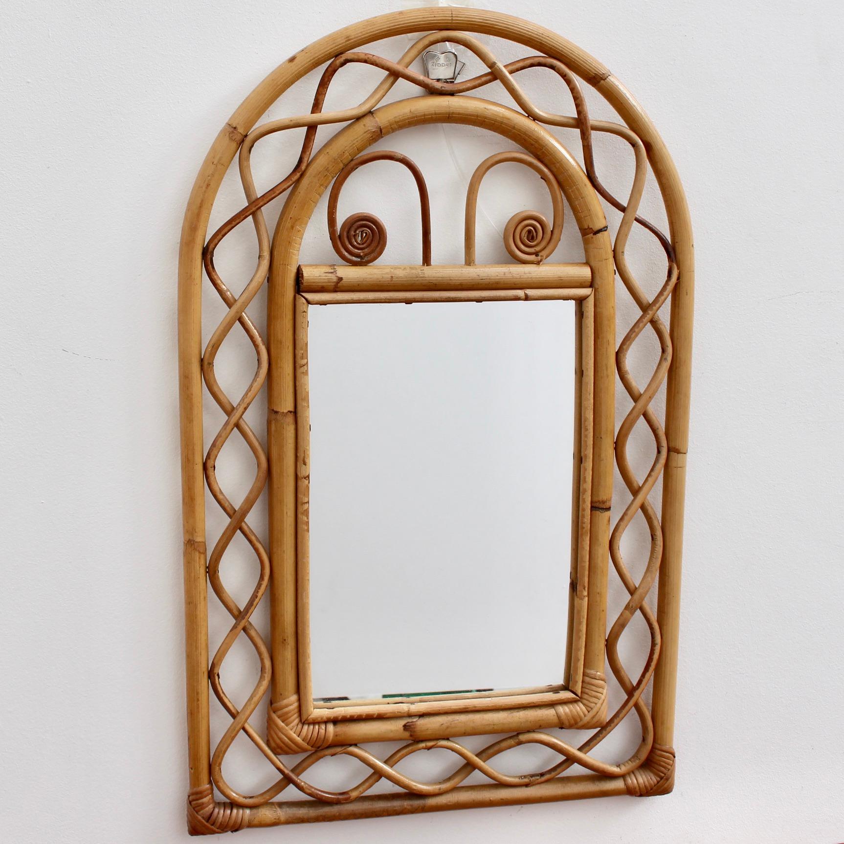 Vintage French rattan wall mirror, (circa 1960s). This is a Byzantine-inspired design with inner and outer frames connected by parabolic shapes of rattan cane. The right-angled corners are lashed together and protected with rattan strands.