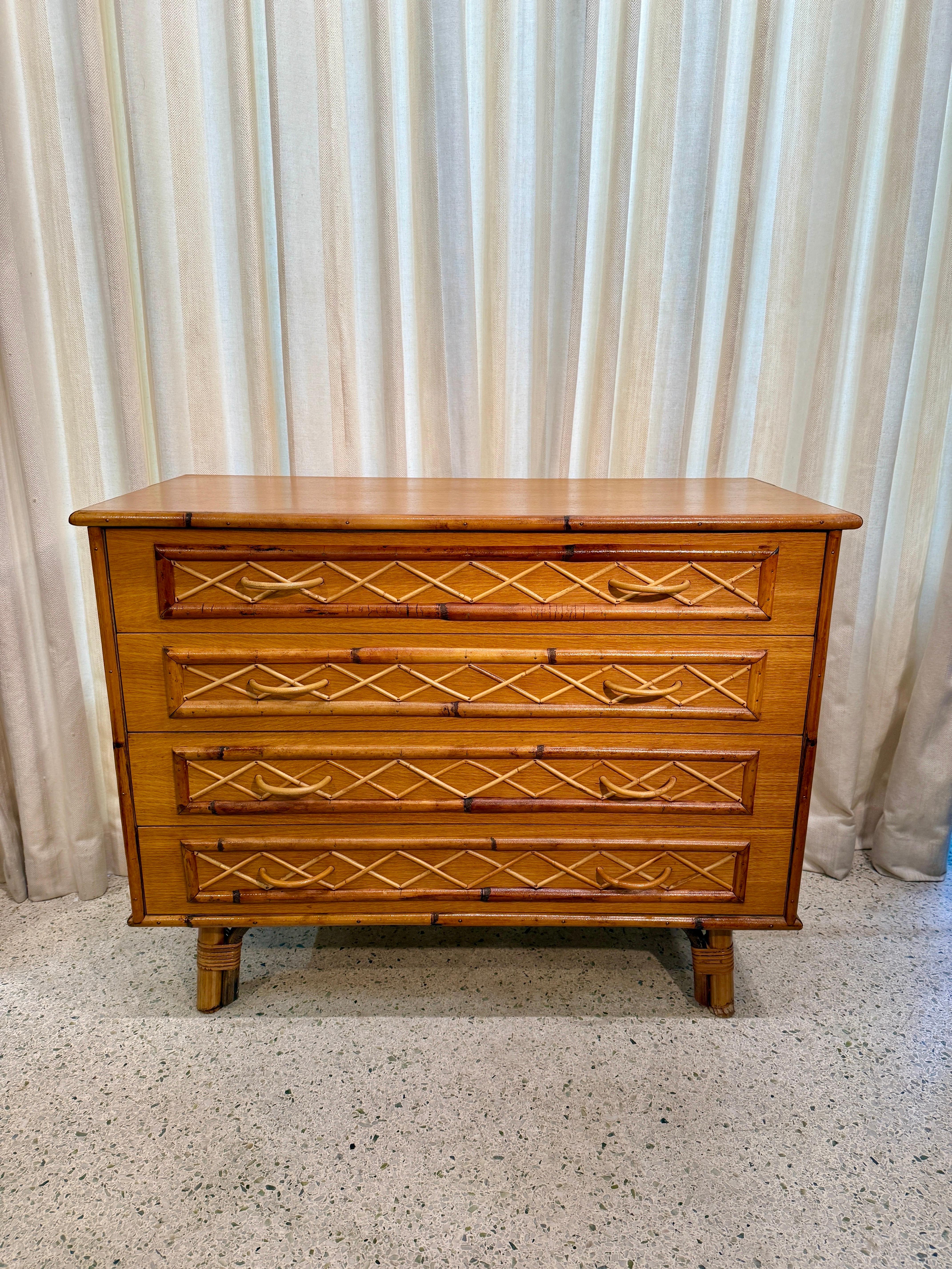 This chic French Riviera 1960's four-drawer chest adorned with unique lattice bamboo details to front and pulls in bamboo. Flare out rattan legs make for some drama and the color is just a perfect patina.