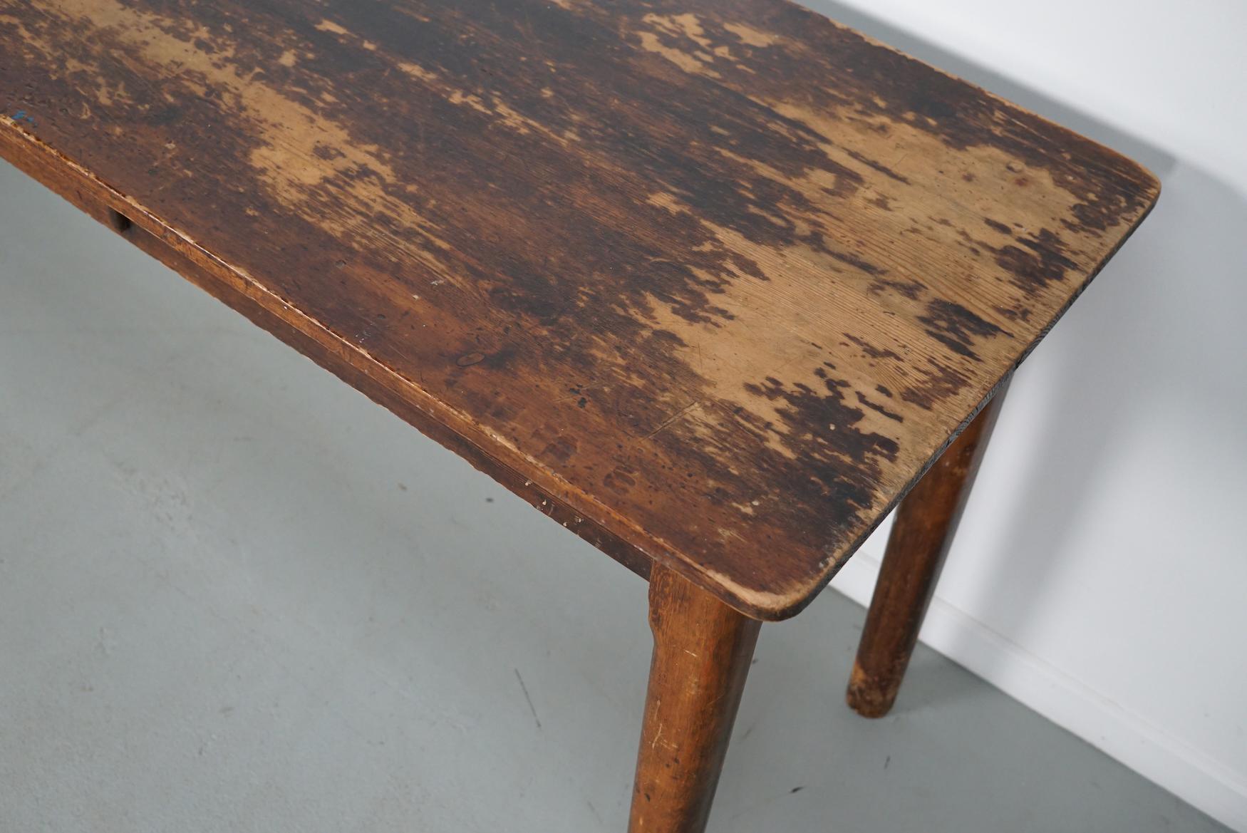 This elegant table was made from pine and oak circa 1950 in France. It features round legs and a drawer with cast iron pull. The table shows many signs of use and age and has a warm color. It could also very well be used as a desk.