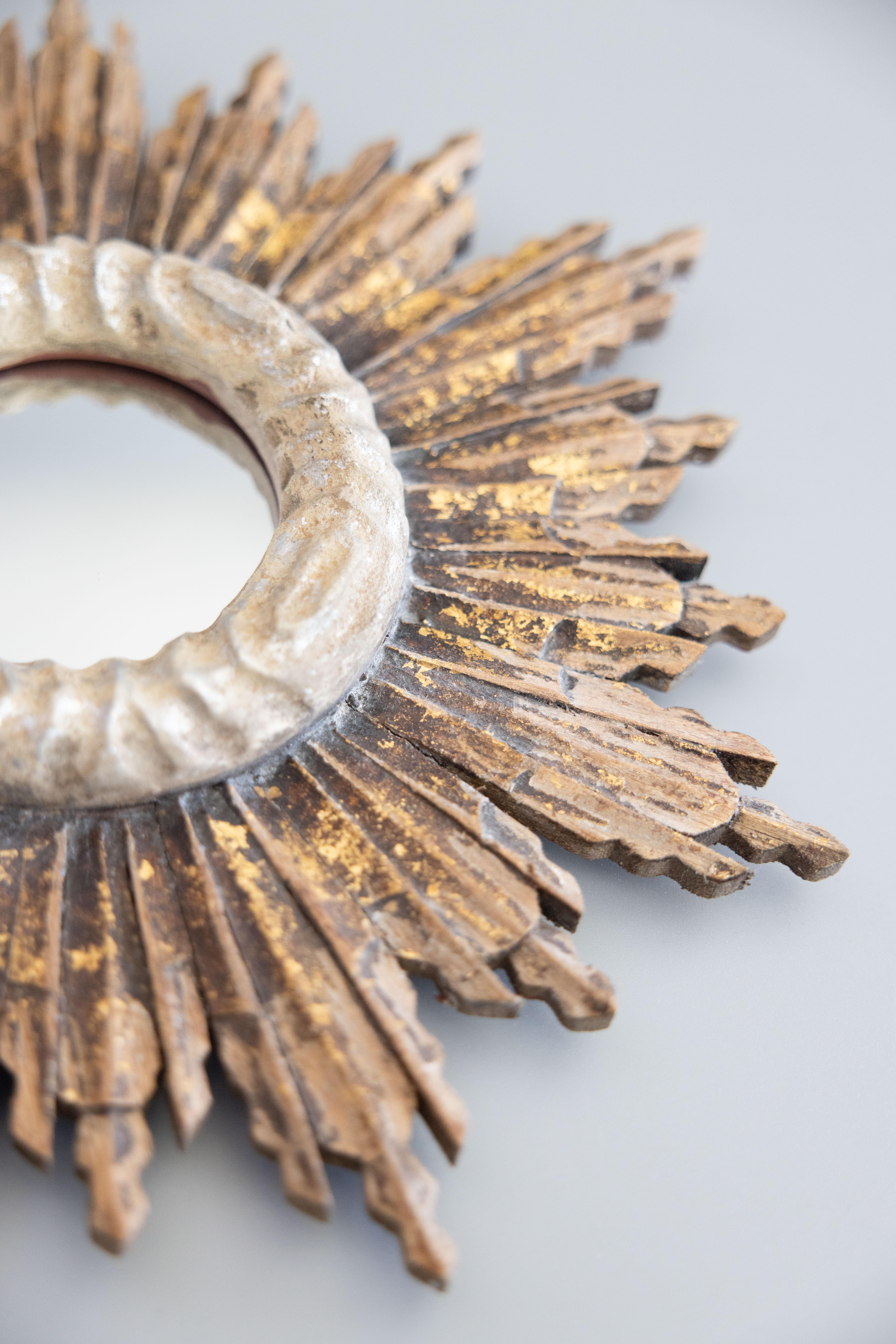 Uno splendido specchio d'epoca francese in legno dorato a raggiera. Questo elegante specchio è circondato da una cornice decorativa argentata e da deliziosi raggi intagliati di lunghezza alternata con una bella patina dorata rustica e distorta.