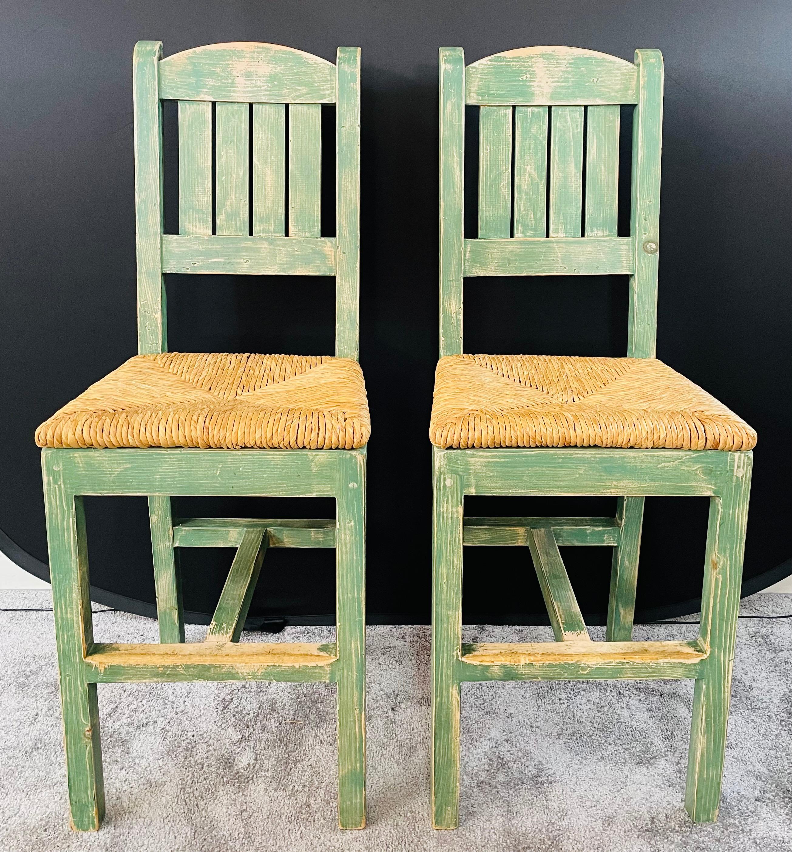 An exquisite pair of vintage French rustic style straw seat bar stools , featuring a distressed green turquoise color. The stools frame is made of wood and the handwoven straw seat is made is a nice triangles motif. The stylish stools will be a nice