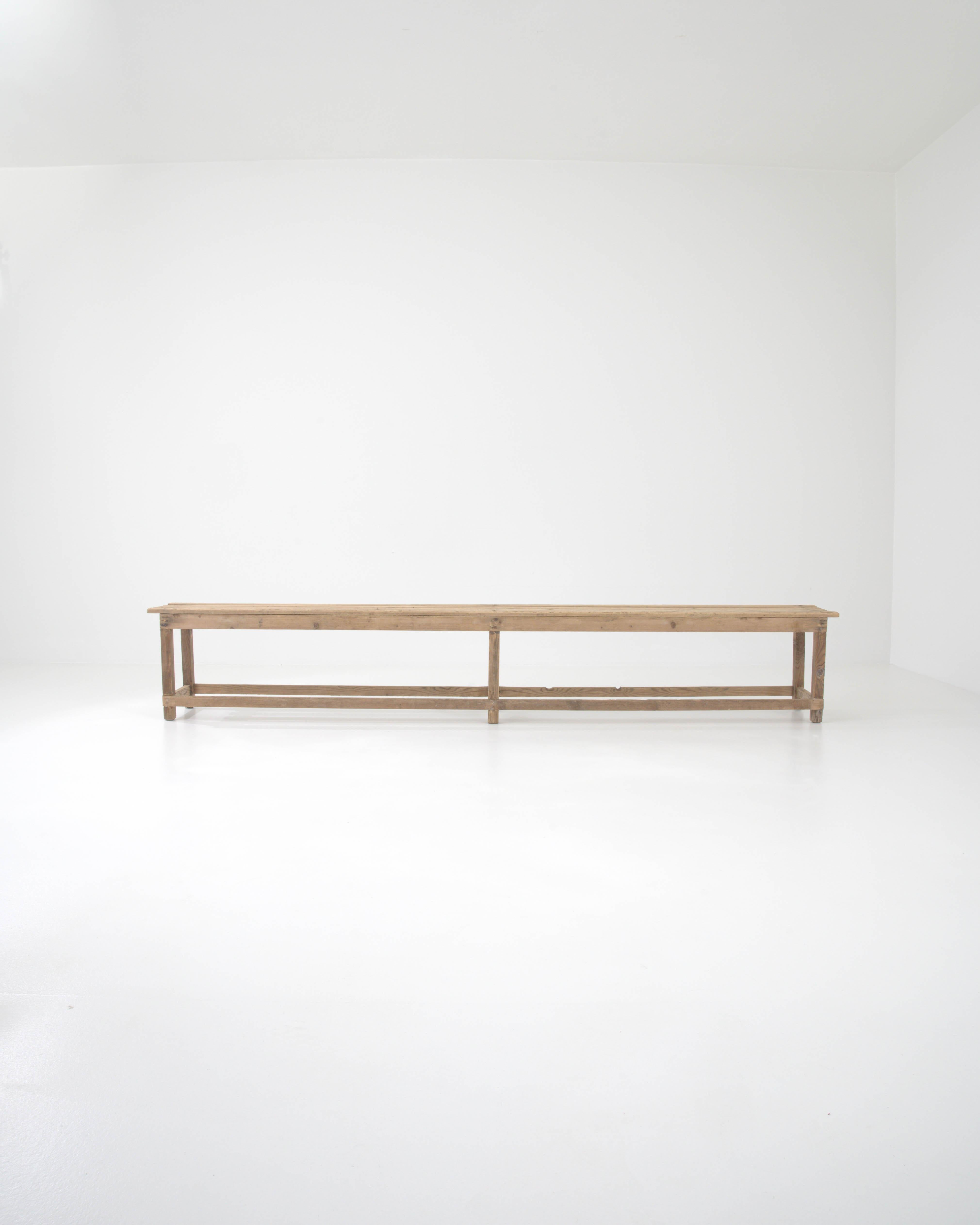 A wooden bench made in France circa 1900. A picture of country minimalism, this 10 foot long bench exemplifies both straightforward craftsmanship and the joy of simple, vernacular design. Long and slender, it offers extensive surface space, but not