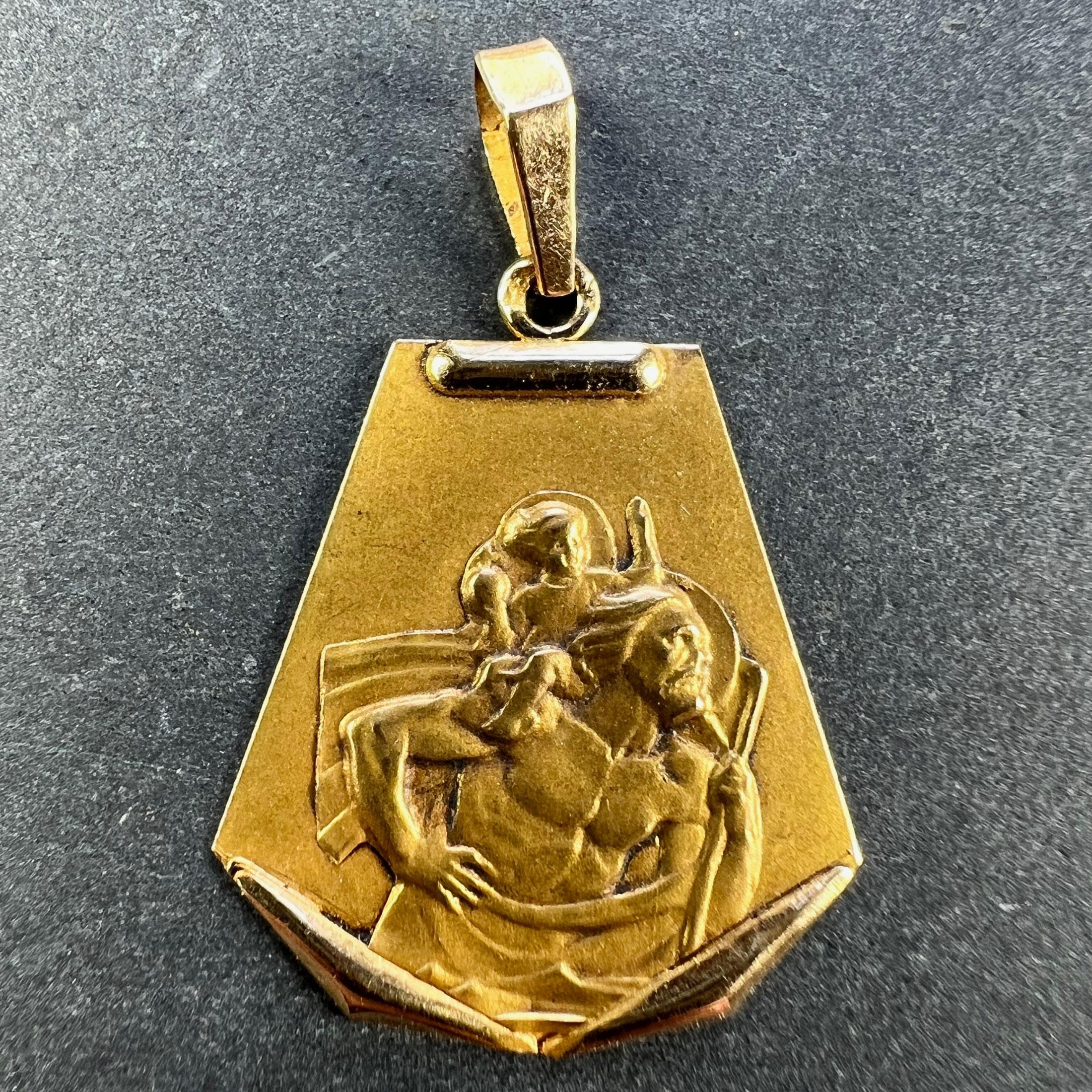 A vintage French 18 karat (18K) yellow gold charm pendant or medal depicting St Christopher carrying the infant Christ across the river. Partially stamped with the eagle's head for French manufacture.

Dimensions: 2.4 x 1.9 x 0.1 cm (not including