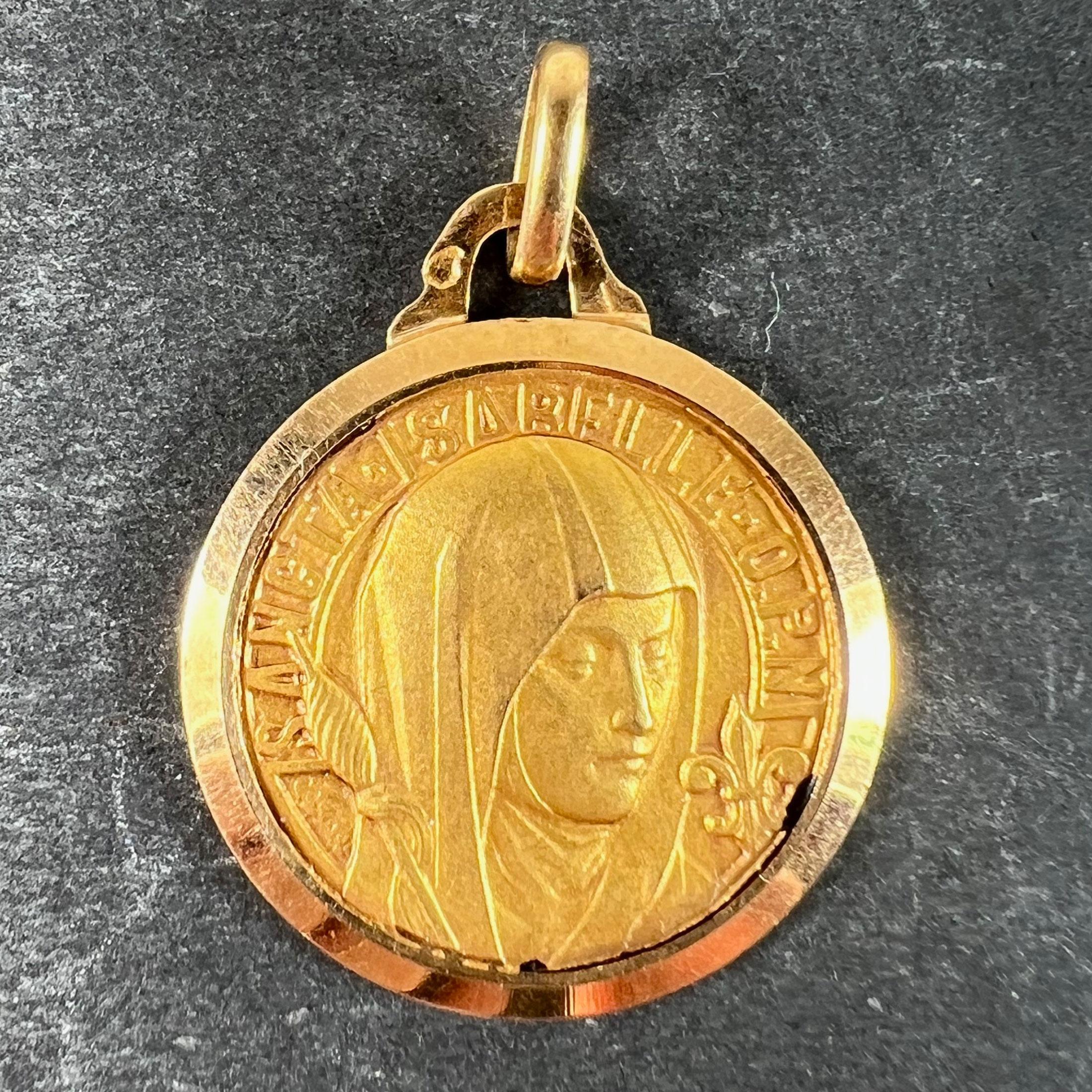 A vintage French 18 karat (18K) yellow gold charm pendant designed as a medal depicting Saint Isabelle of France with a fleur de lys emblem and a spindle. St Isabelle was revered as being the patroness of the sick.

Stamped with the eagle's head