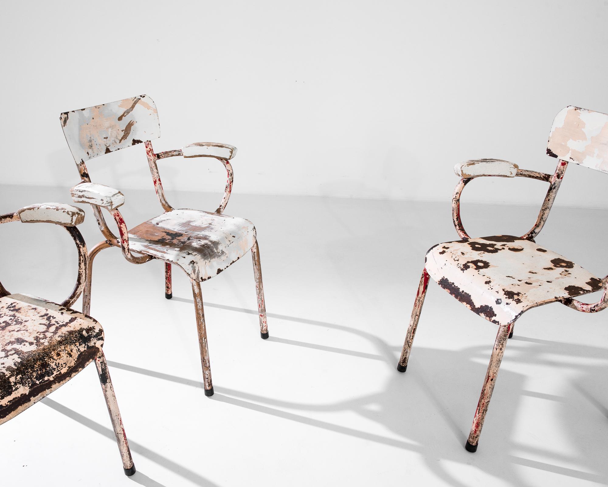 Un ensemble de quatre chaises d'école vintage avec des accoudoirs hauts fabriqués en France vers 1950. Ces authentiques chaises en métal présentent des dossiers bas et des pieds légèrement anguleux qui rappellent les chaises en bois courbé modernes.