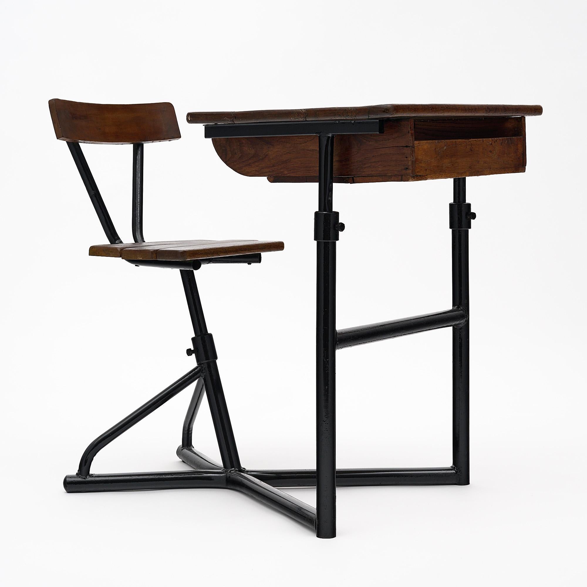 Moderner französischer Schulschreibtisch aus der Mitte des Jahrhunderts mit einem schwarz lackierten Stahlgestell, das sowohl einen verstellbaren Holzstuhl als auch einen verstellbaren Holzschreibtisch mit einer Schreibfläche und einem Fach trägt.