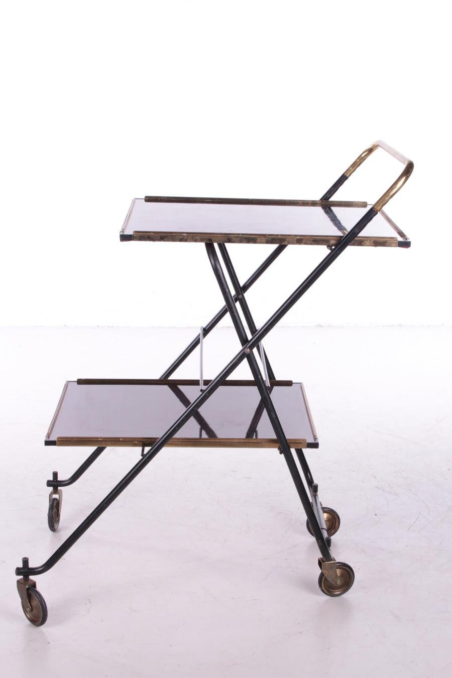 Vintage French Serving Trolley or Drinks Trolley, 1960s

Serve food and drinks in style with this chic French 1950s trolley.

The typical sleek frame is made of gold-colored brass with black metal, the top is made of shiny wood that gives the whole