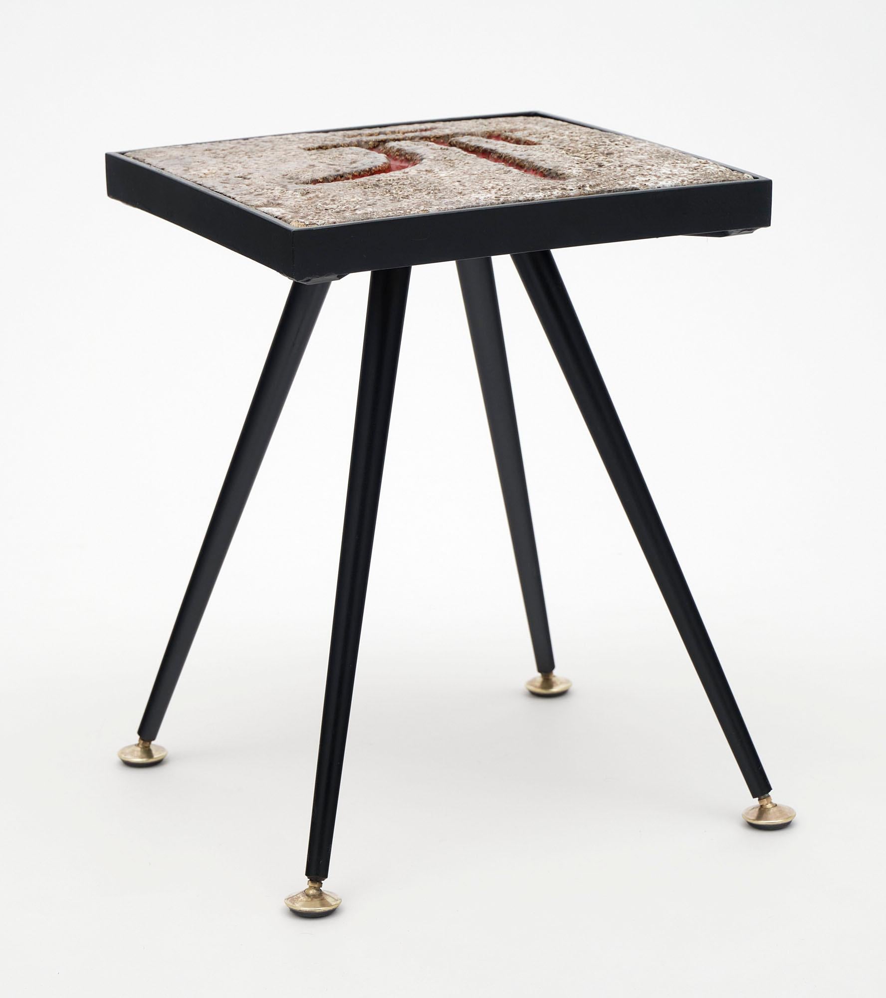 Side table from France made with painted textured ceramic top and black lacquered steel base.