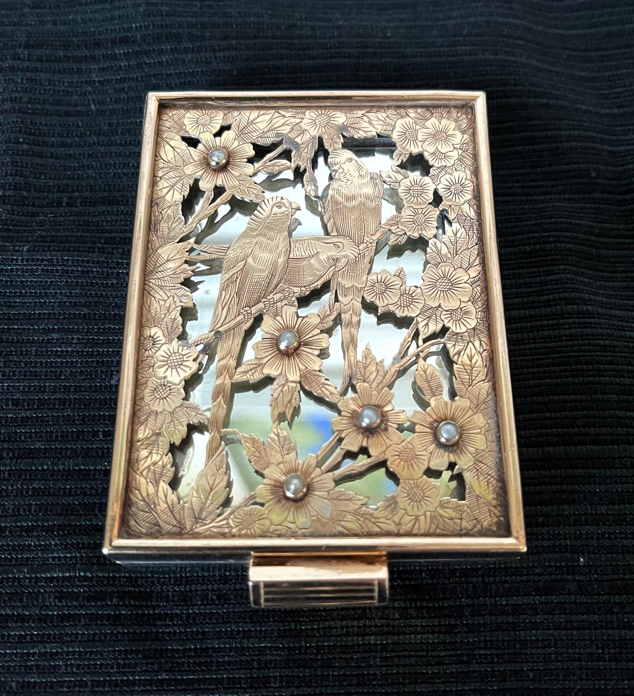 A stunning silver compact case with gilt by Boucheron Paris circa 1930s-1940s, of Art Deco period and style. The silver case features an iconic façade with a pierced and chased three parrots perching on flowering branches set with five mini pearls.