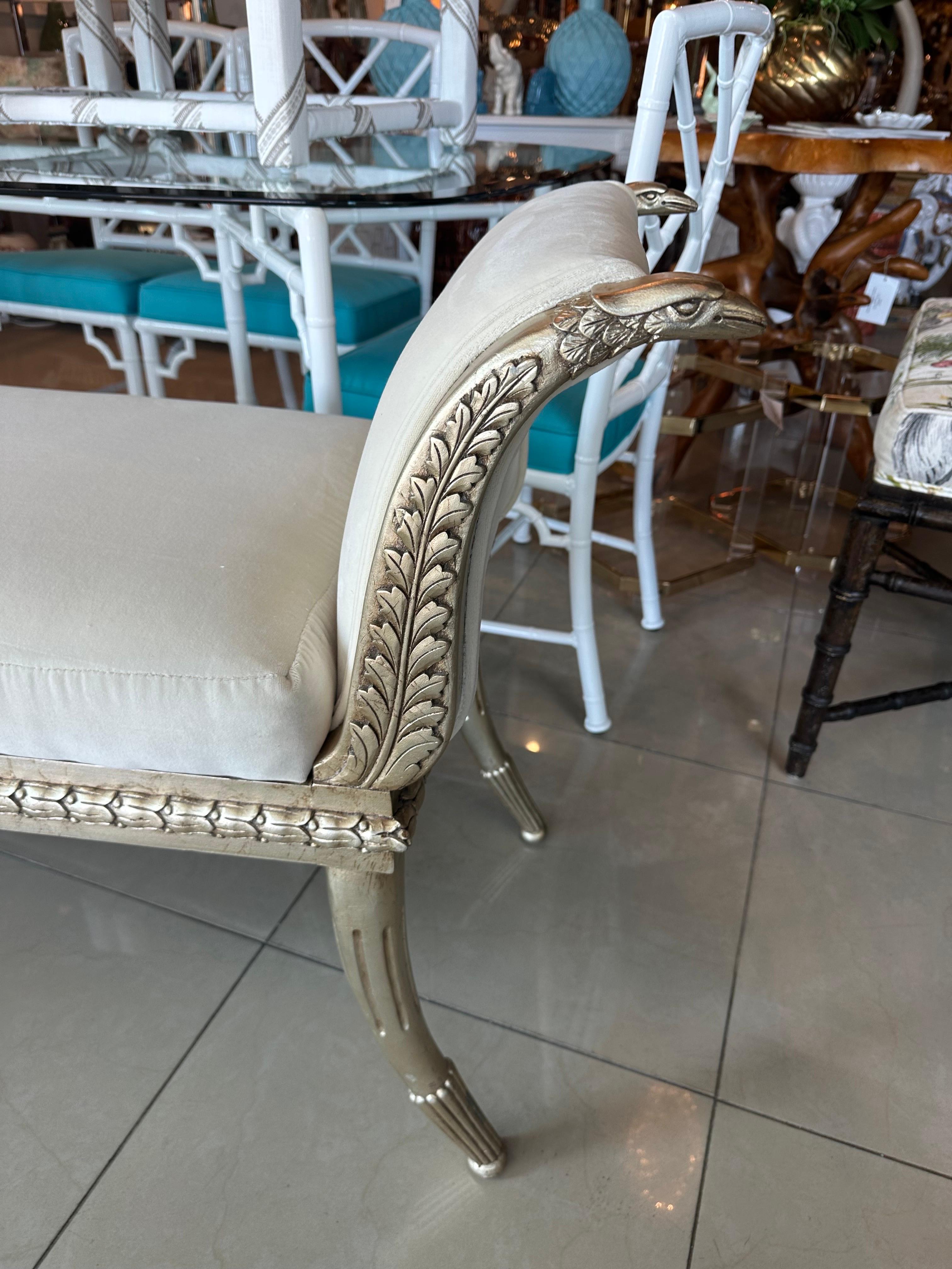 Beautiful 1940s French neoclassical hand painted silver gilt wood bench with bird swan ends, tapered flare lags. Newly upholstered in an ivory velvet by Schmaucher. Dimensions: 59 L x 20 D x 30.5 H, Seat Height 22.
