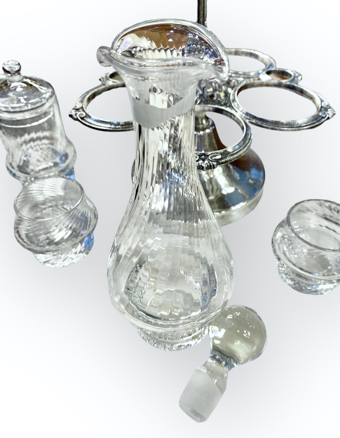 A vintage French silver plate cruet set with optic glass oil and vinegar bottles with stoppers, salt and pepper pots, and a covered mustard pot all in a caddy with a simple pedestal base. The glass has a beautiful lilting shimmer to it.

A lovely