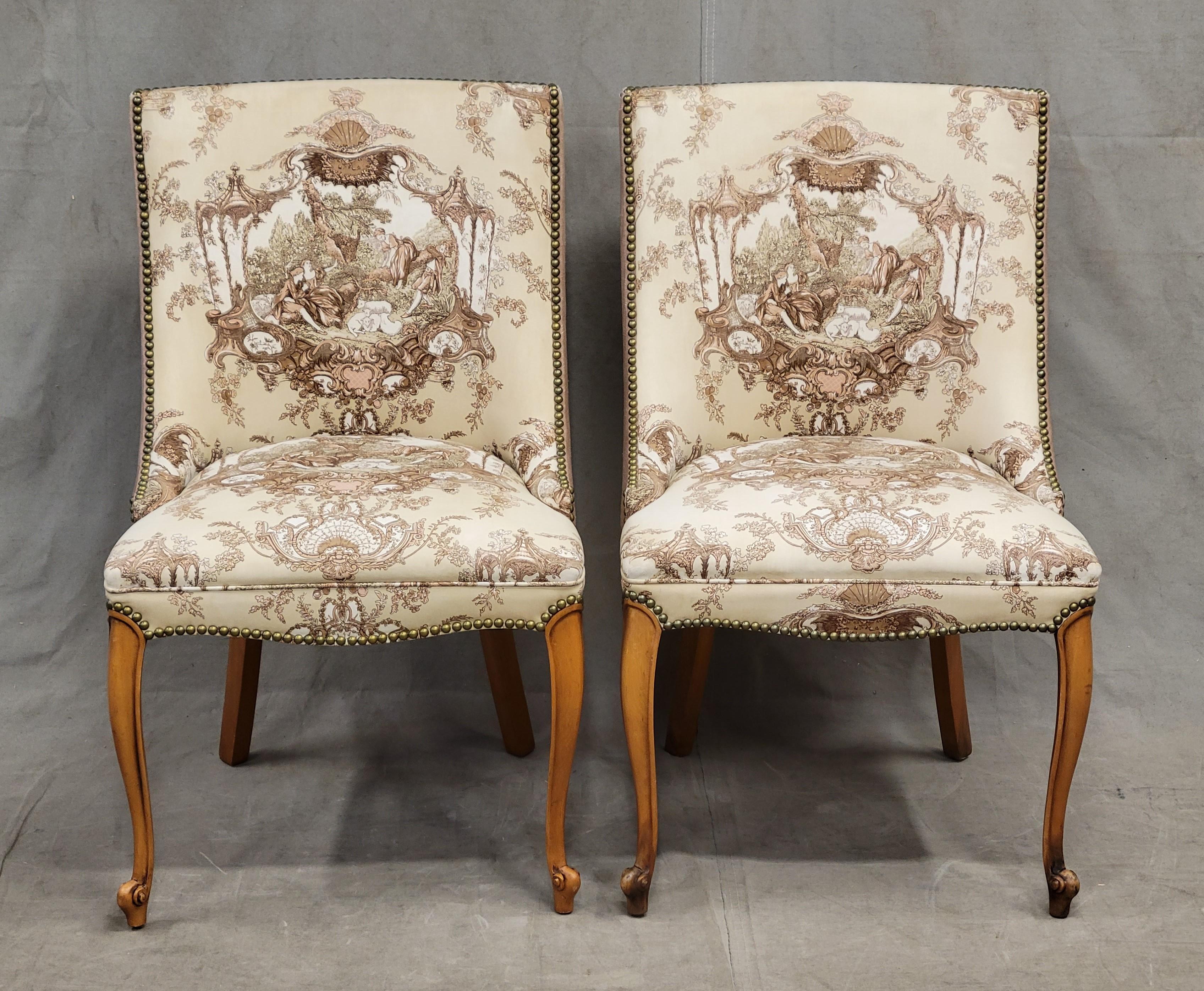 A charming and well made pair of vintage, likely 1950s or 60s, French slipper chairs with mauve, tan, pink and cream toile upholstery on the front. Back side is a beautiful solid mauve linen-like fabric. Accented with brass tacks. Extremely