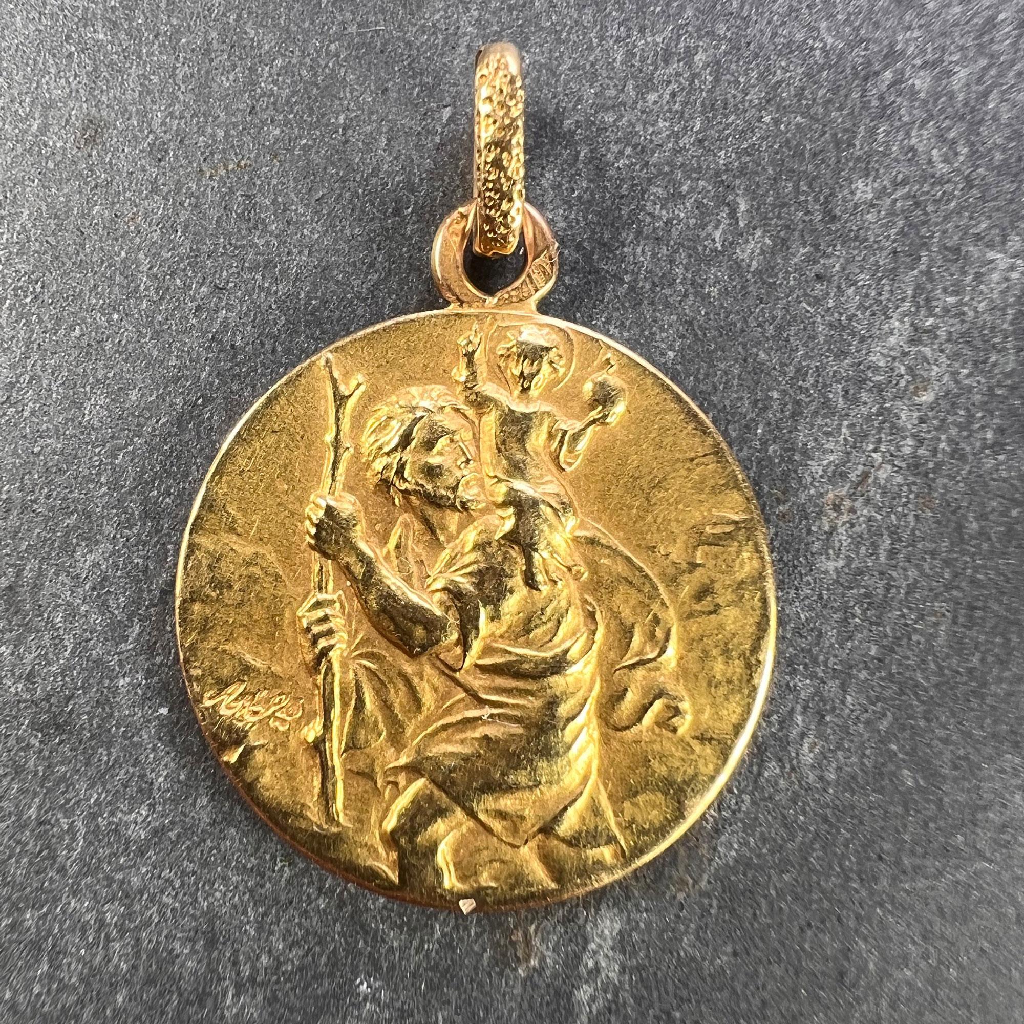 A French 18 karat (18K) yellow gold charm pendant depicting St Christopher as he carries the infant Christ across a river with an unknown signature. The reverse depicts the Triumph of Speed via a couple driving a car through a landscape. Stamped
