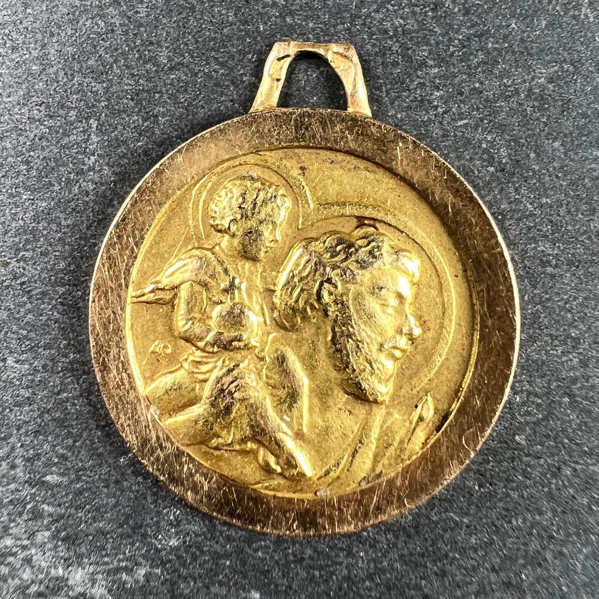 A French 18 karat (18K) yellow gold charm pendant depicting the head of St Christopher as he carries the infant Christ across a river. Stamped with the eagle’s head for French manufacture and 18 karat gold, and an unknown maker’s mark. The sculpted