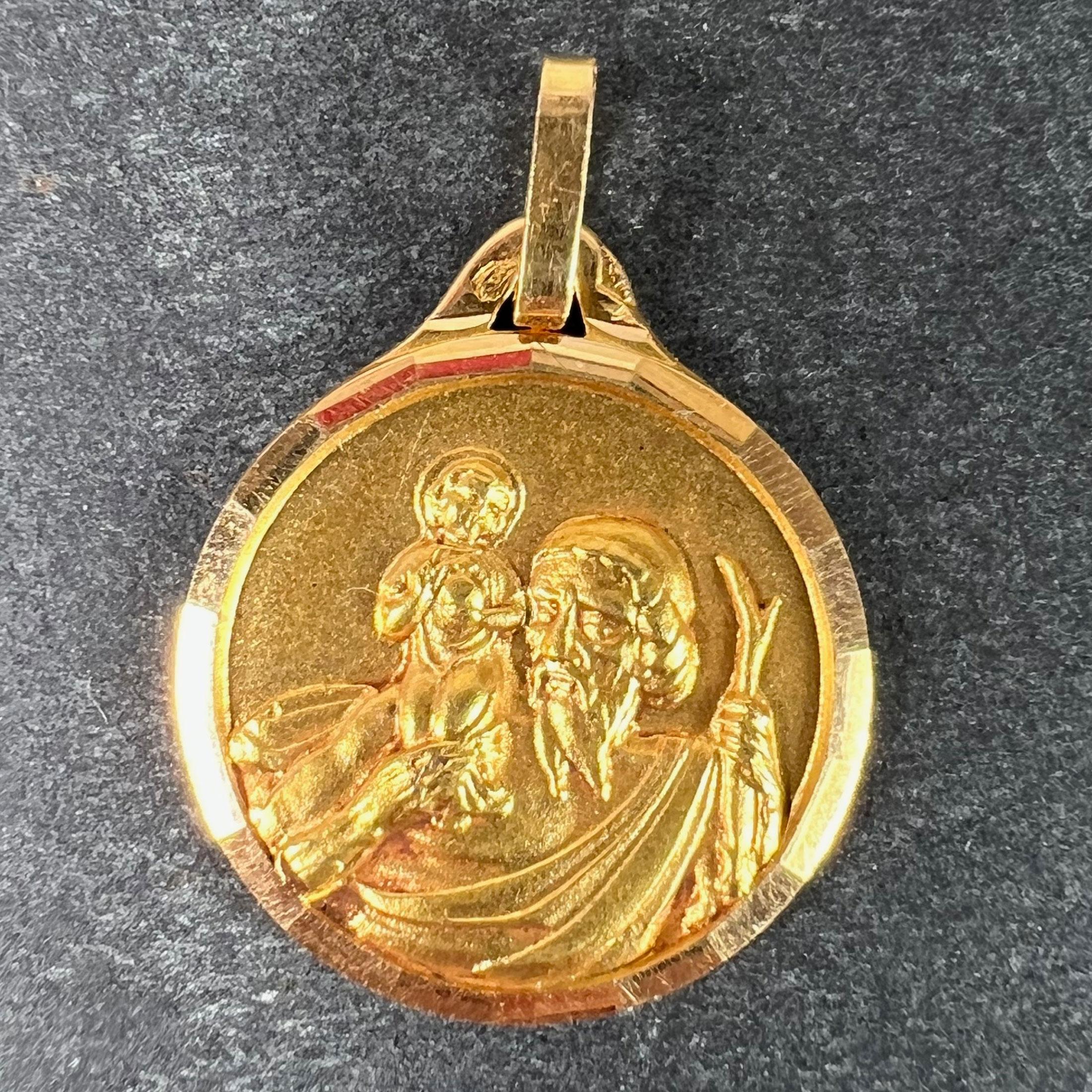 A French 18 karat (18K) yellow gold charm pendant depicting St Christopher as he carries the infant Christ across a river set in a faceted gold frame. Stamped with the eagle’s head for French manufacture and 18 carat gold, and an unknown maker’s