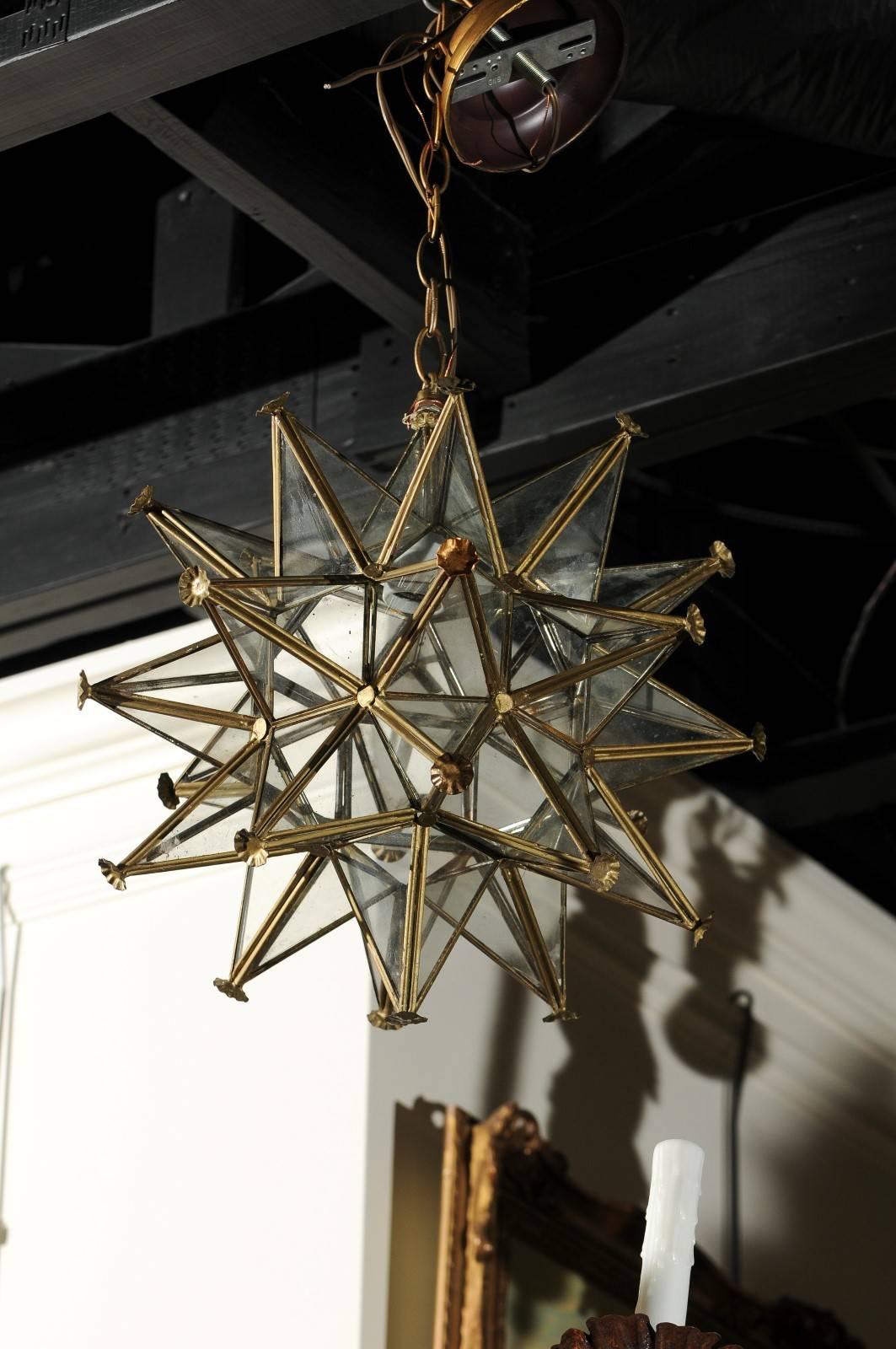 A French vintage star light fixture from the mid-20th century with gilt metal frame and new wiring. This French light fixture features an energizing star shape. A gilt metal frame, accented with delicate flower-shaped cups, secures the various glass