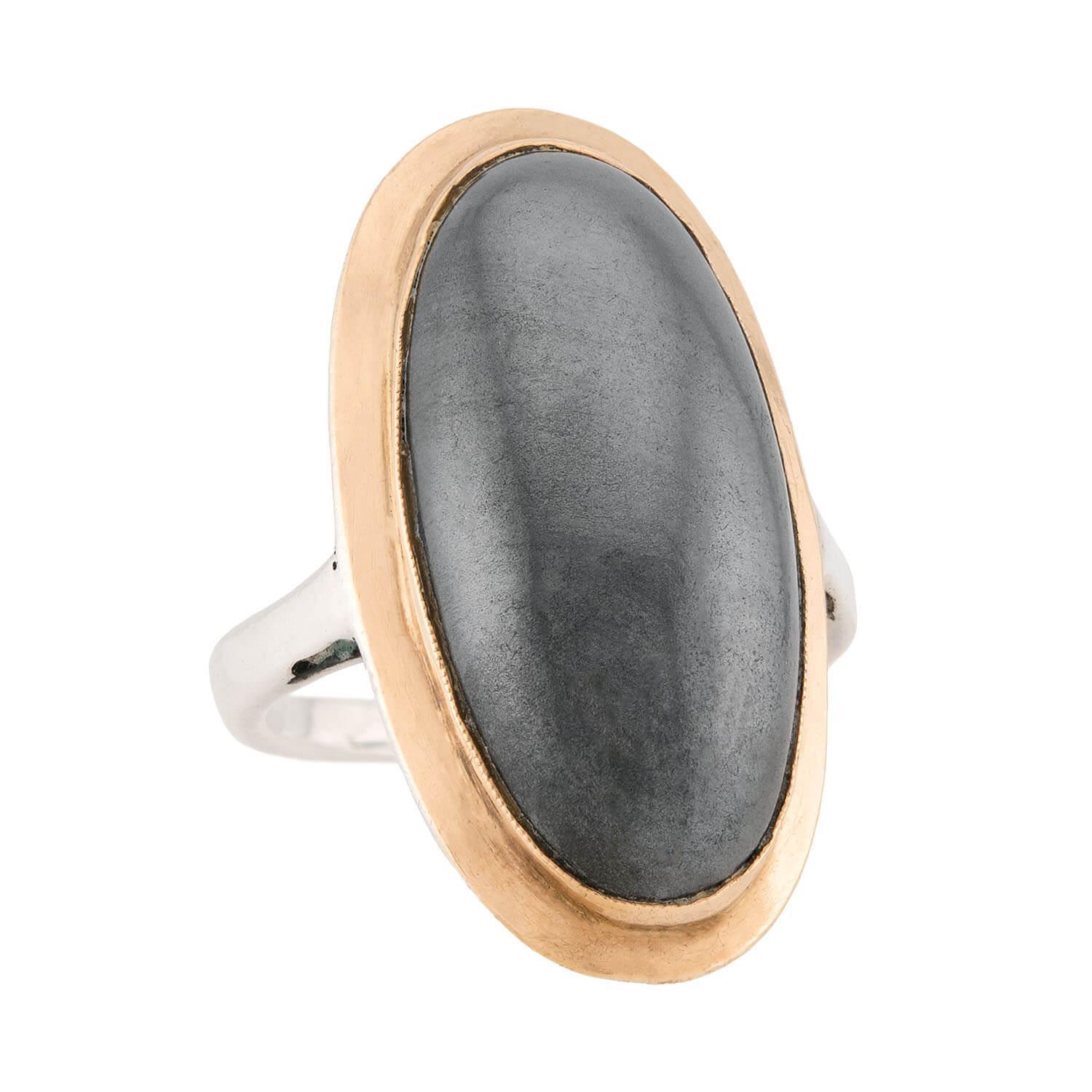 A stunning hematite ring from the Vintage (ca1950s) era! Crafted in sterling silver and 18k rose gold, this ring features an oval-shaped hematite cabochon. The hematite is held within a simple bezel setting and is surrounded by a smooth and simple