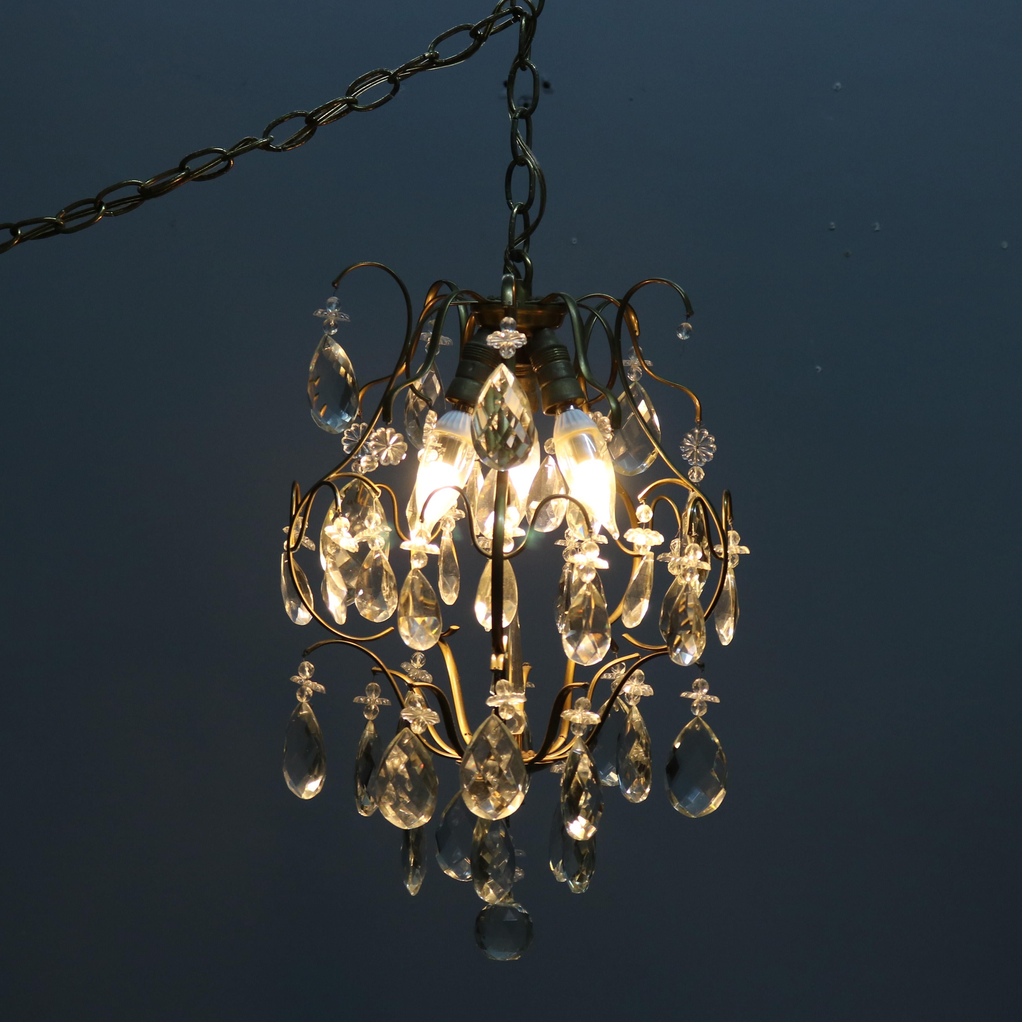 A vintage French style hall chandelier offers scrolled brass frame with hanging crystals throughout, circa 1940

Measures: 17