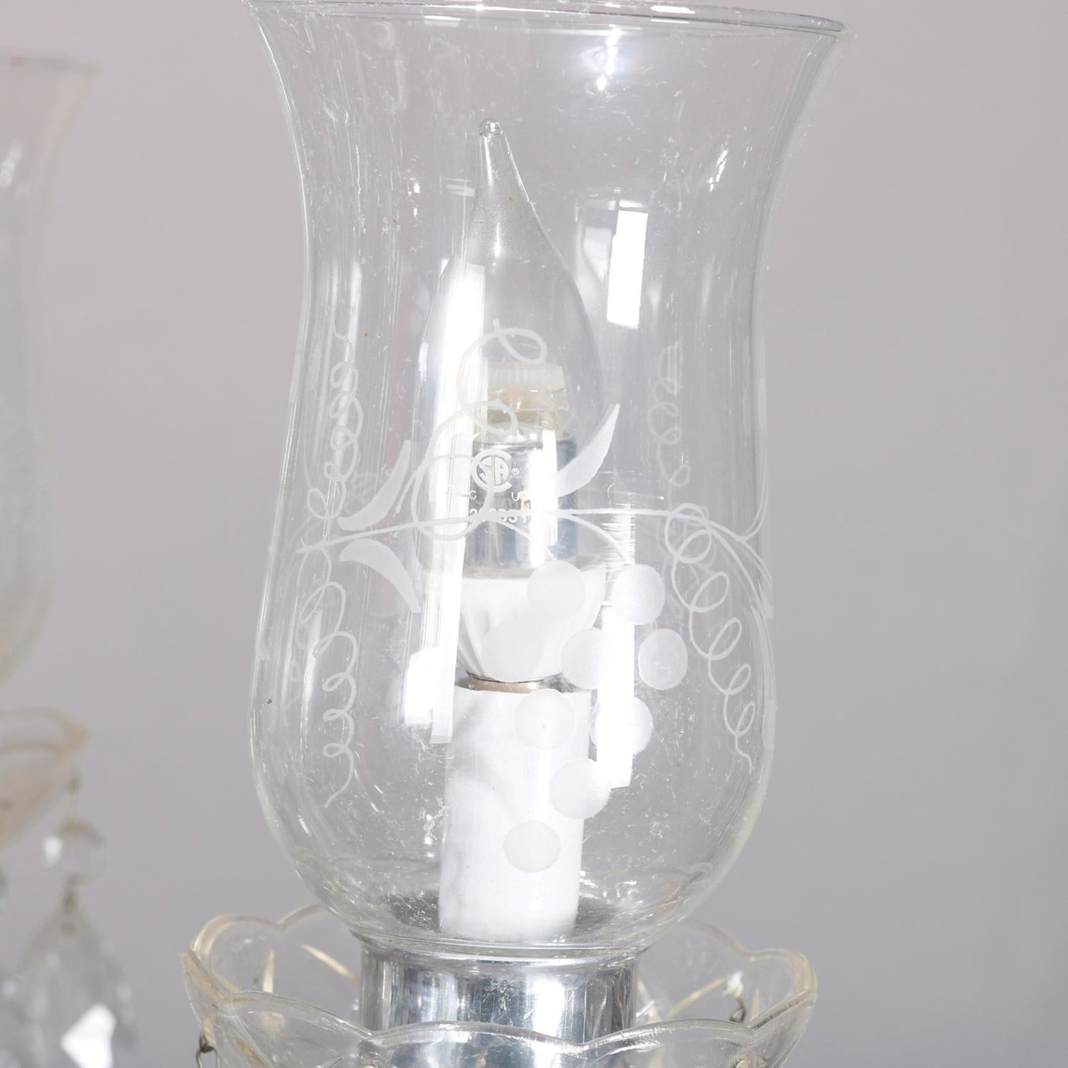 A vintage French style crystal chandelier offers chrome frame with scroll form arms terminating in candle lights with etched glass shades, cut crystals throughout, circa 1950


Measures: 30