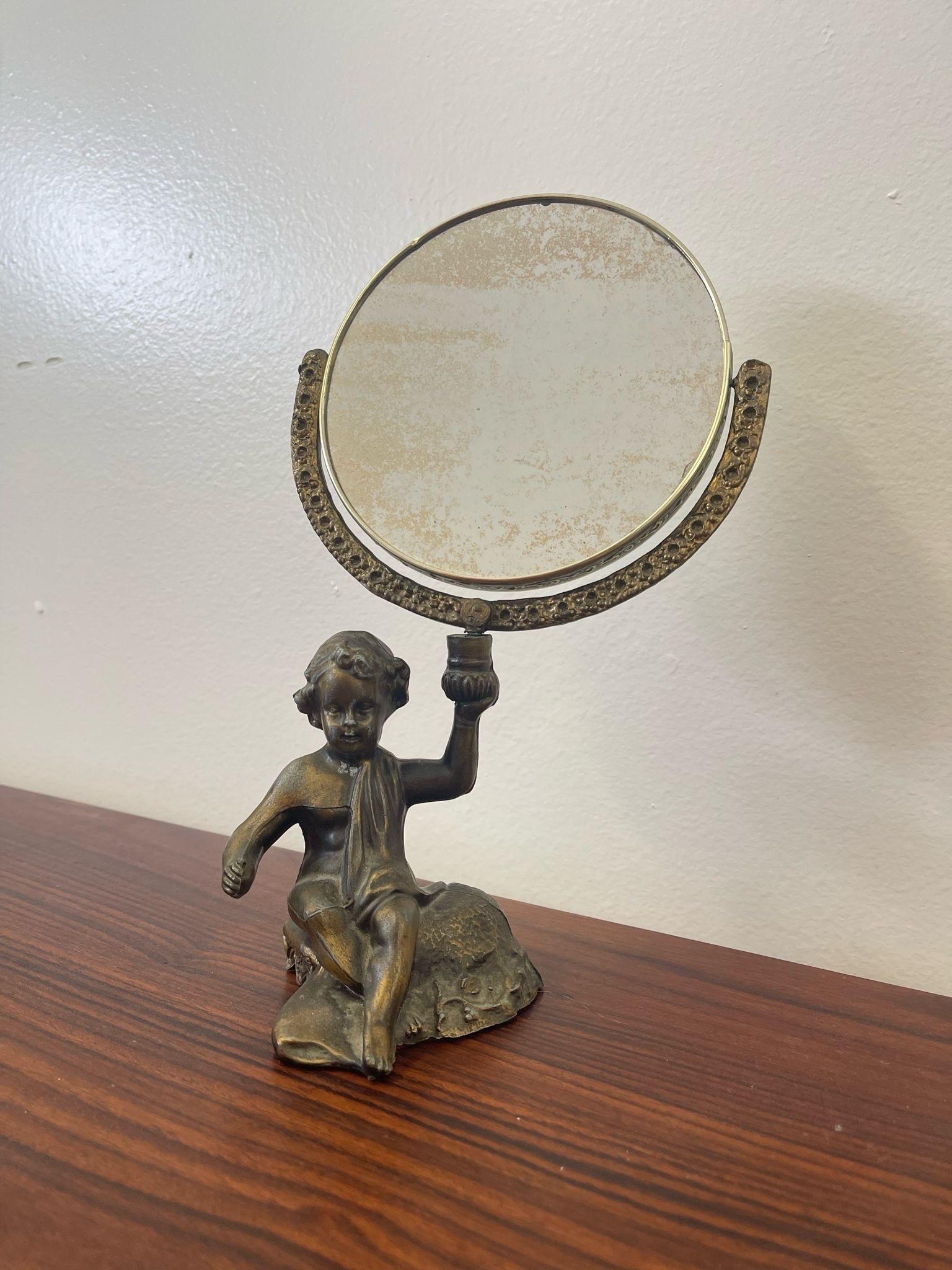 This mirror has intricate detailing throughout. The Cherub is shown holding the mirror up with his hand. Petina in the glass shows beautiful aging. Vintage Condition Consistent with Age as Pictured.

Dimensions. 7 W ; 4 D ; 12 H