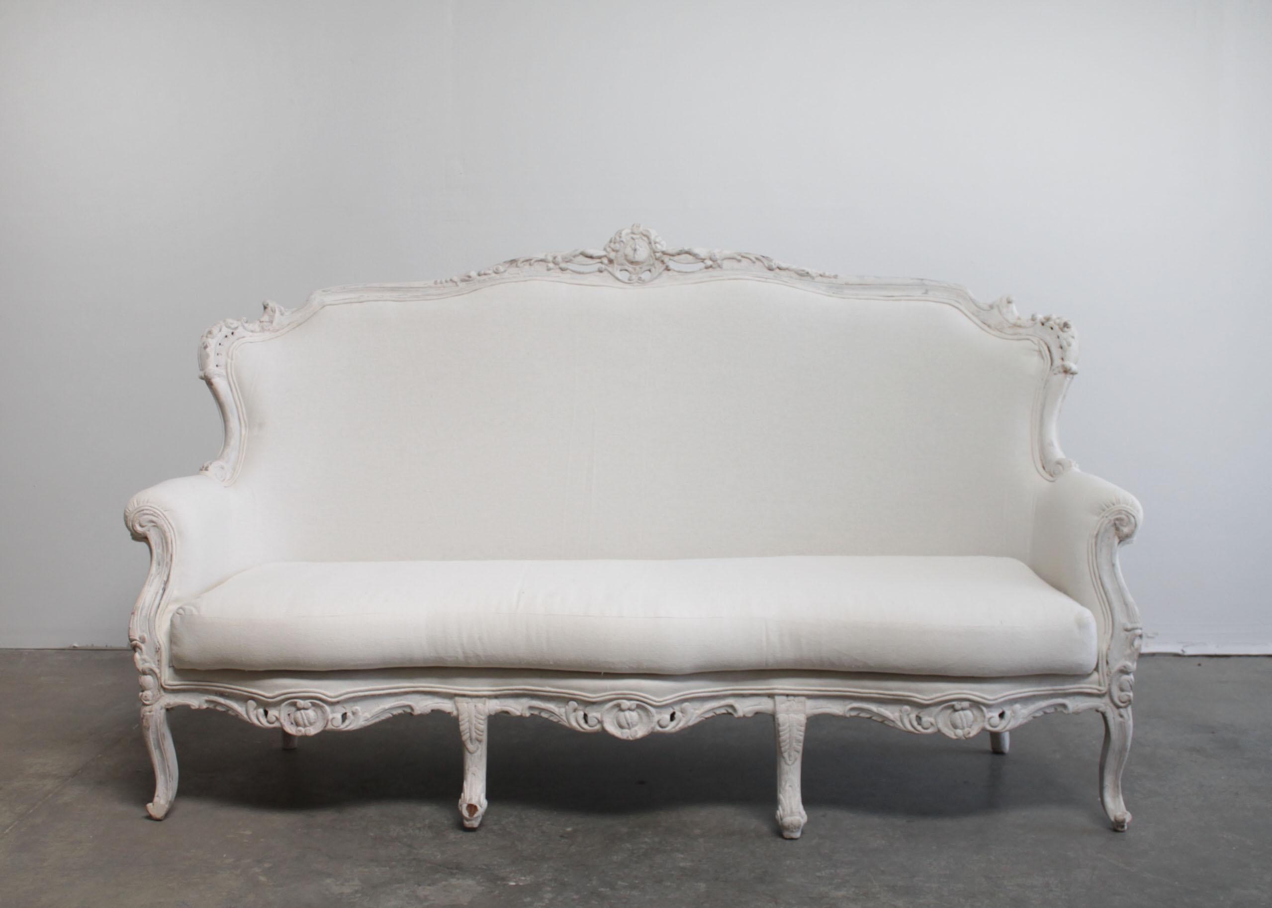 Vintage painted and upholstered Louis XV style sofa
Painted in a French white with subtle distressed edges, where wood shows through.
Beautiful curved legs, with a medallion carving at the back, and soft scrolls along the bottom deck.
Upholstered