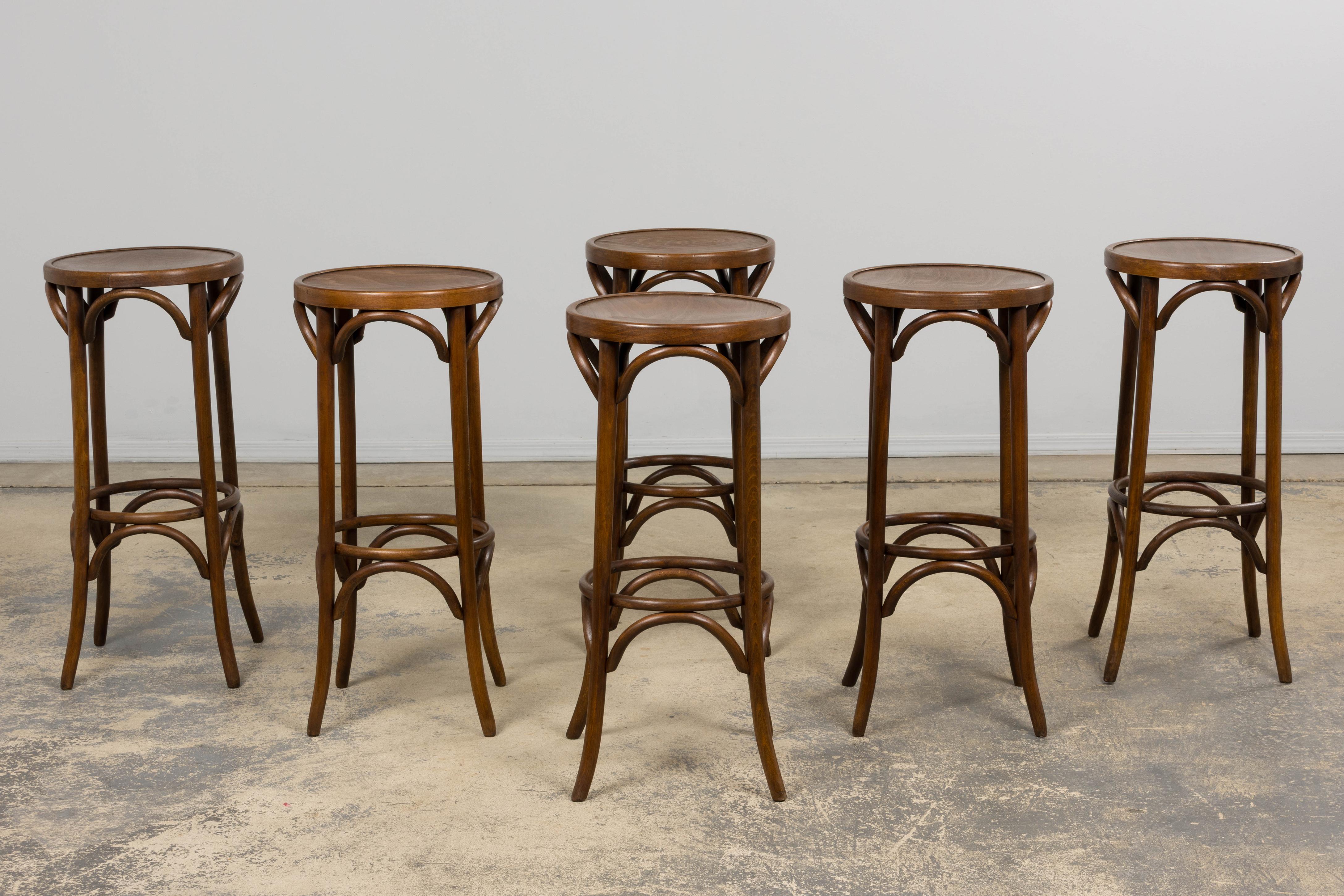 Un bel set di sei sgabelli da bar francesi del XX secolo attribuiti a Thonet, provenienti dalla Provenza. Ogni sgabello è realizzato in legno di bentwood con sedili rotondi e graziosi archi, a riprova dell'intramontabile design francese dei caffè. I