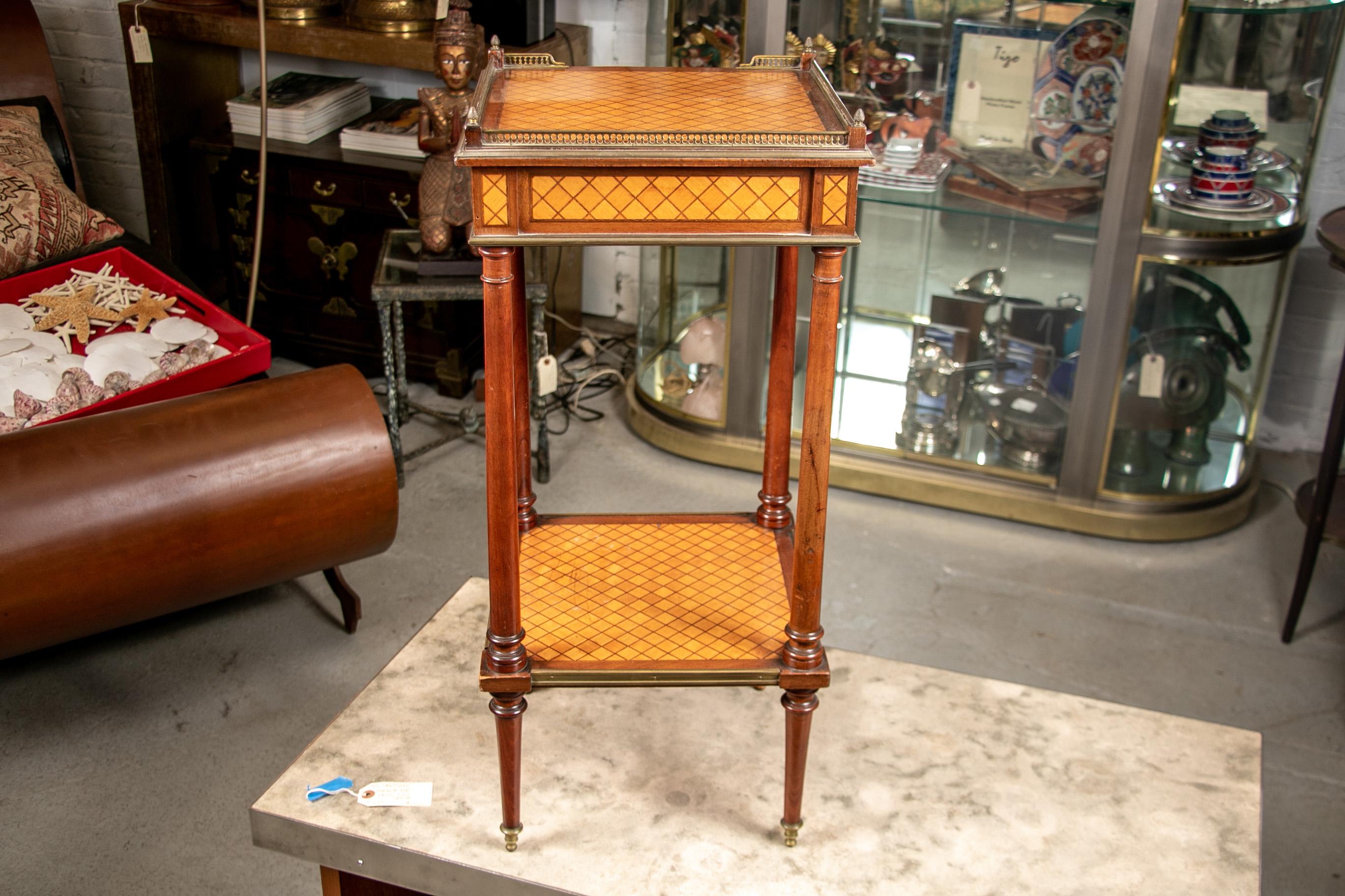 Vintage French tiered parquetry stand, satinwood and mahogany, the tiers with overall diamond patterns, the top with a 3/4 brass gallery. Brass banded frames top and bottom and a single frieze drawer. With turned supports and cylindrical tapering