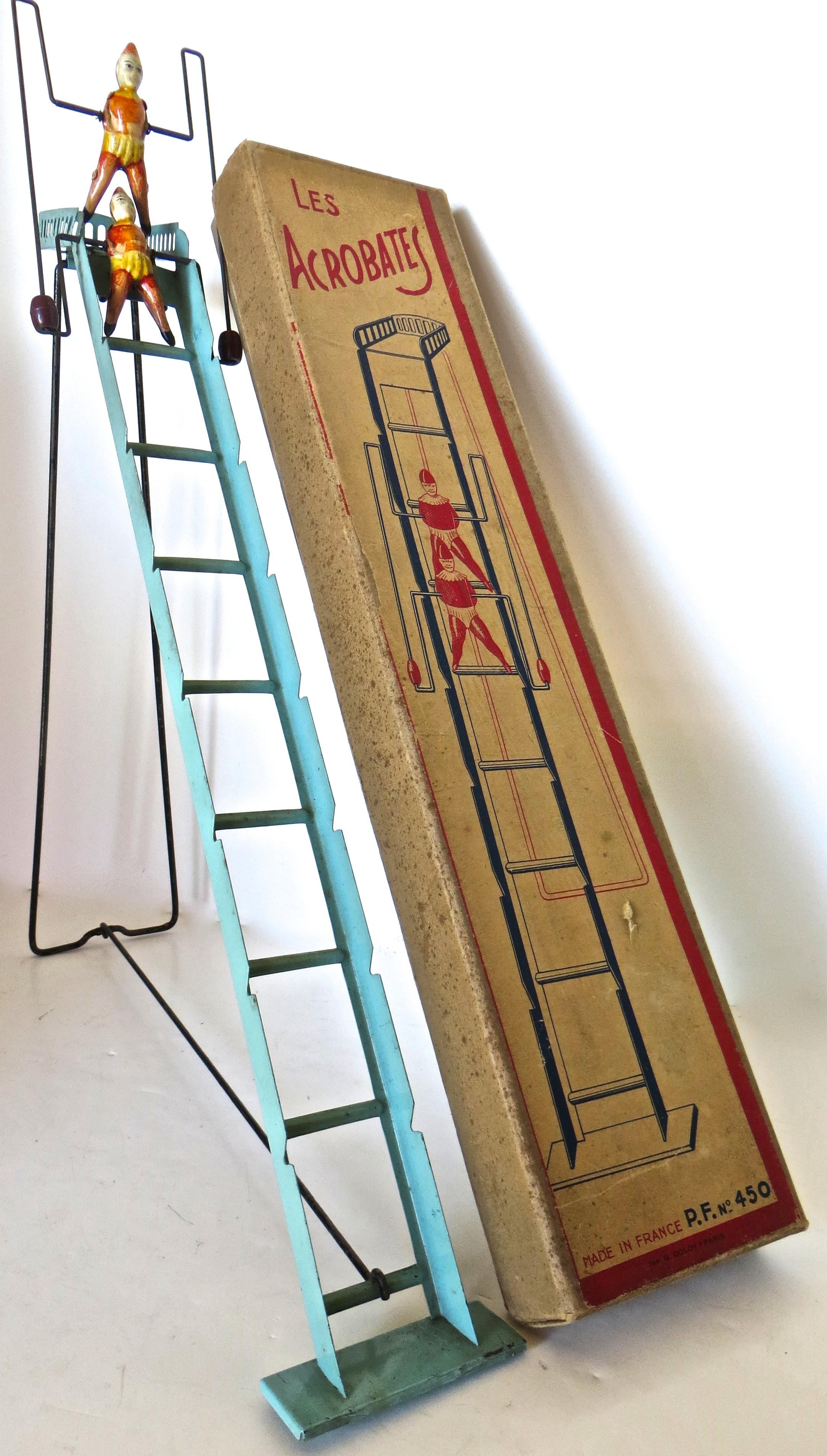 Rare 100 year old French toy in it's original box depicting two acrobats attached to a wire frame with brown barrel weights, cascading down a green metal ladder. Once assembled (loop the hand-painted black support frame over the bottom rung of the