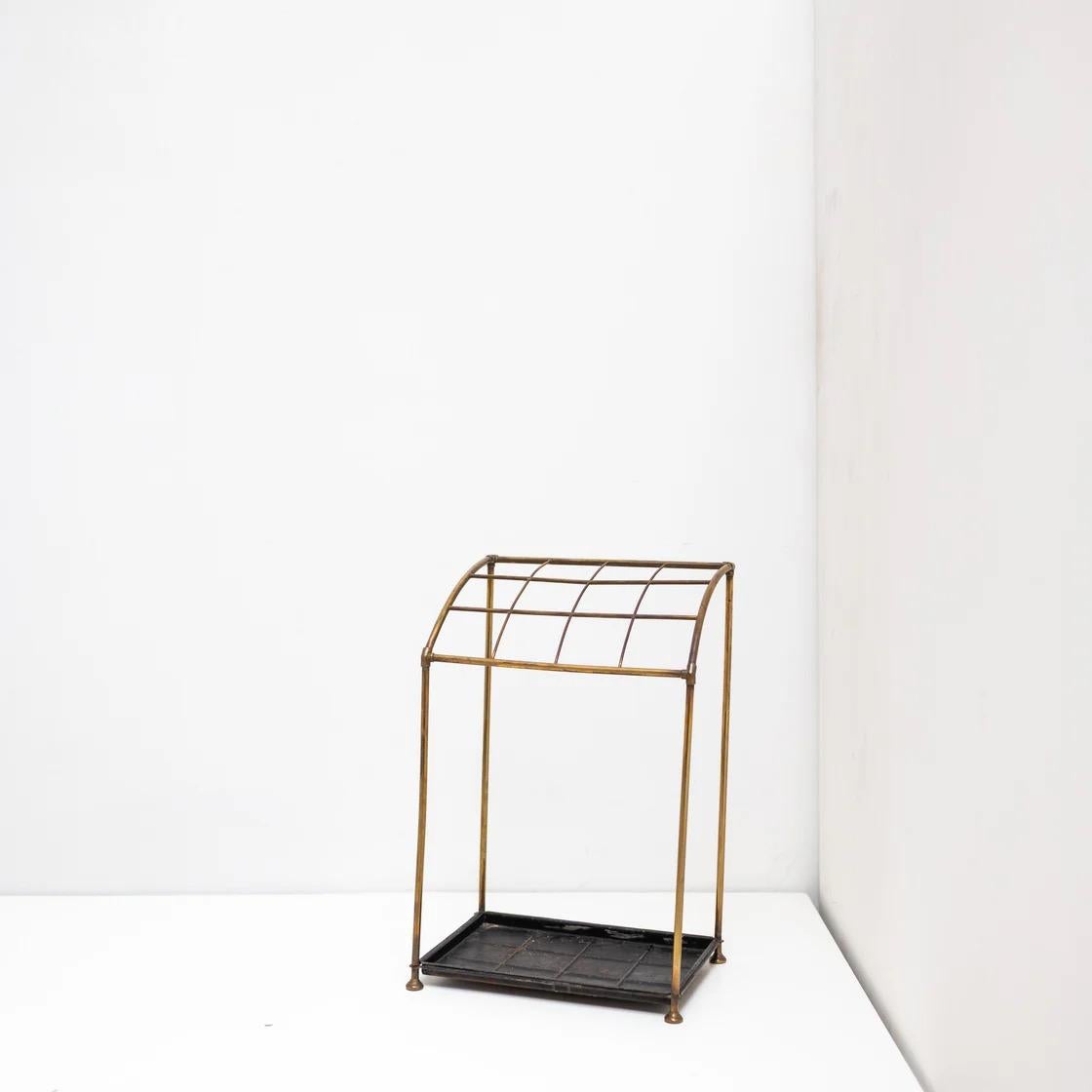 Un raffinato portaombrelli vintage proveniente dalla Francia, caratterizzato da una struttura in ottone curvato e da una base scura. Il suo design è caratterizzato da semplicità ed equilibrio: una struttura geometrica minimale che emana una