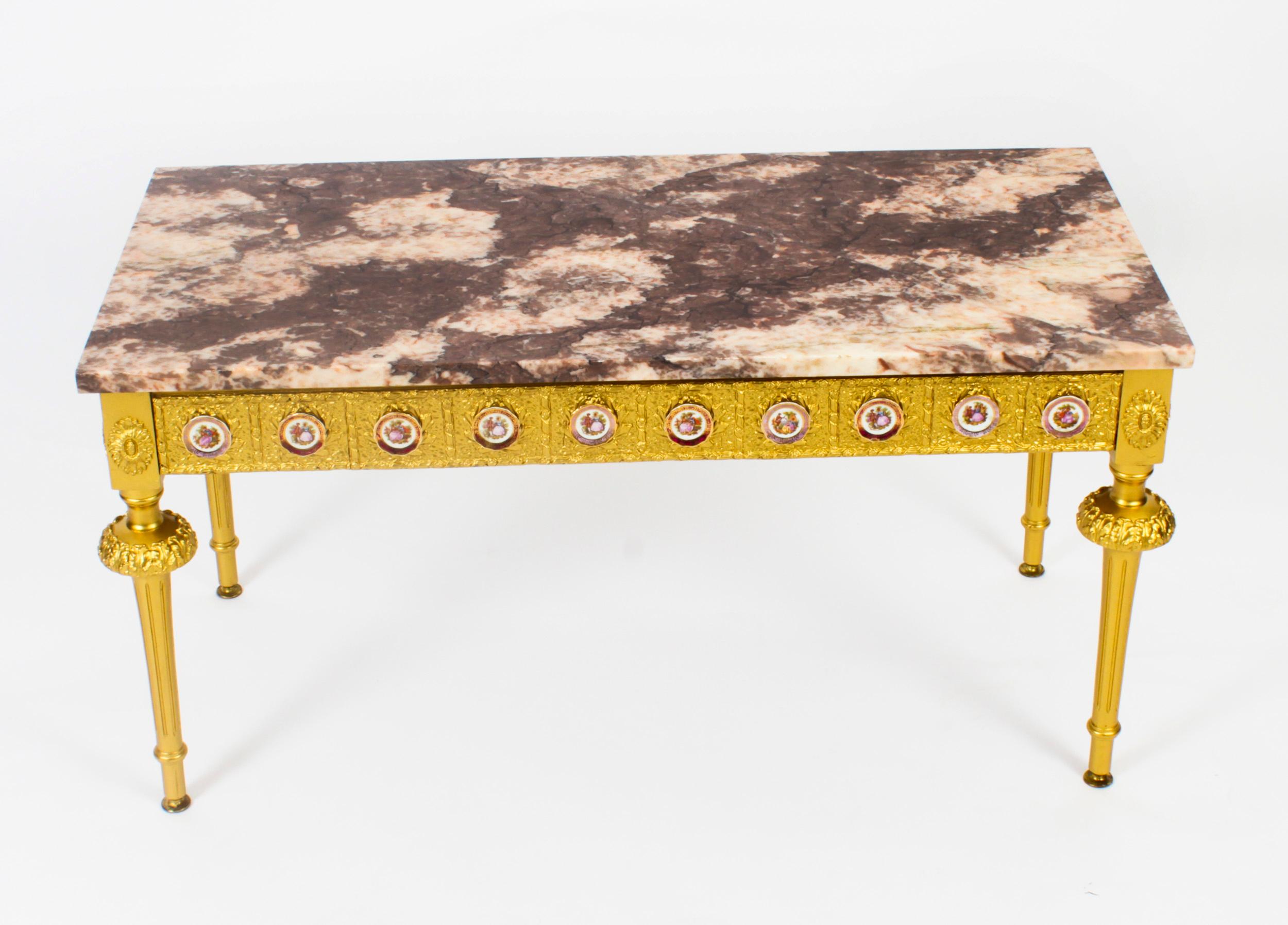 Il s'agit d'une exquise table basse française en bois doré et marbre avec des plaques de Limoges, datant d'environ 1950.

Cette merveilleuse table basse est de forme rectangulaire et possède quatre pieds cannelés effilés élégants et stylés. La