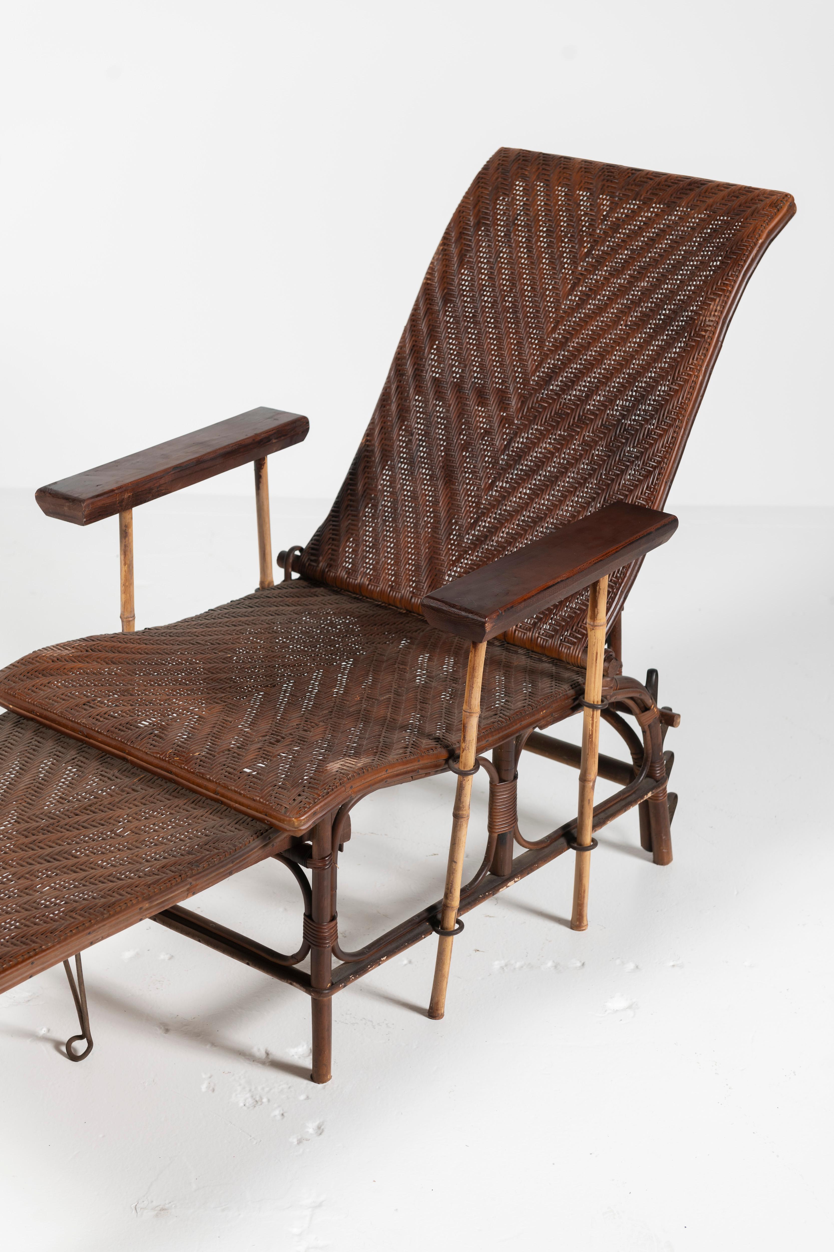 Classic French Wicker and Bamboo Chaise Lounge woven in a chevron pattern in brown. The chair converts to a lounge by extending the ottoman and the back is both curved and adjustable to recline at several angles for comfort and relaxation. The arms