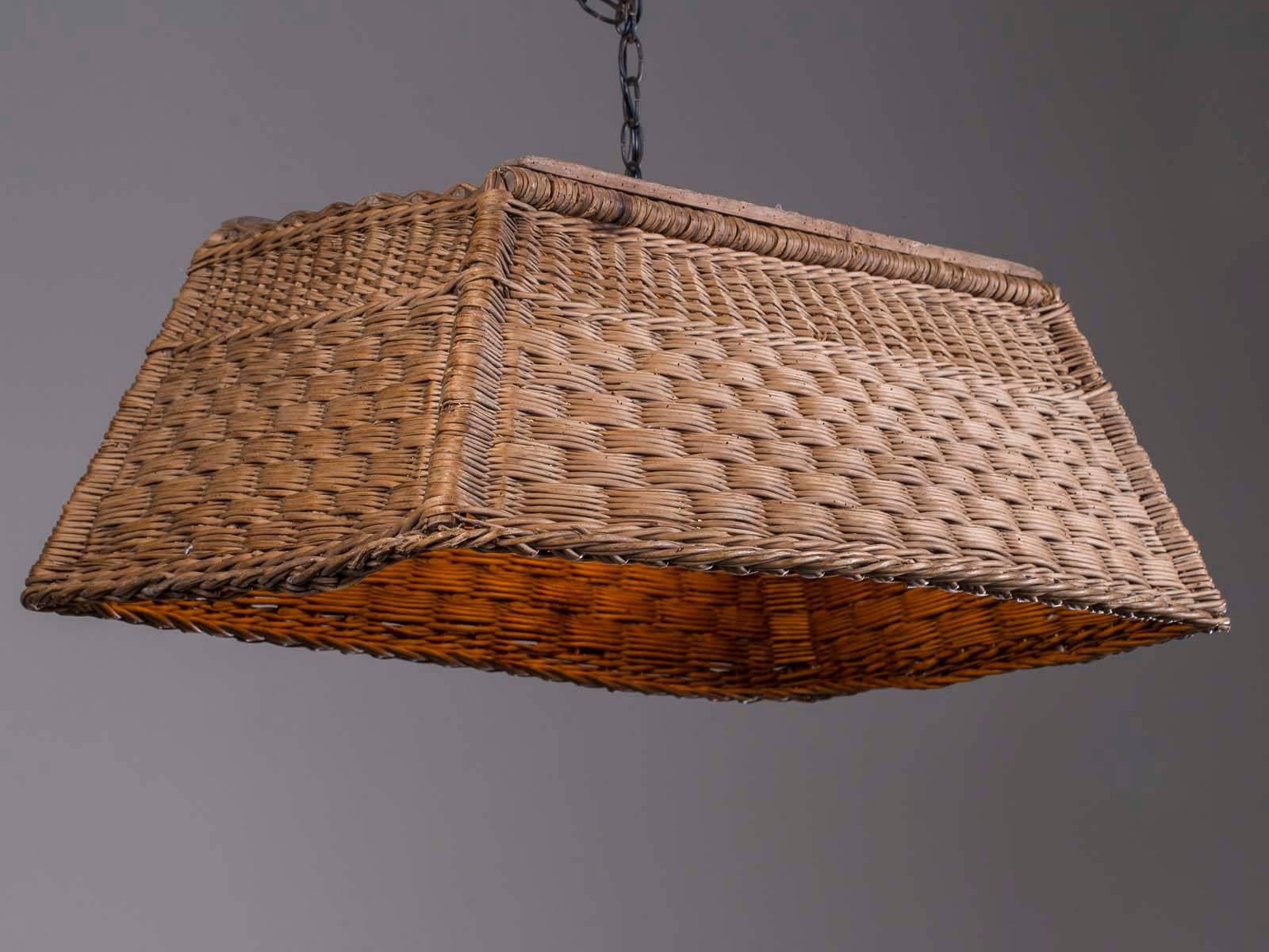 This handsome rectangular vintage French woven wicker basket chandelier from France circa 1920 features a custom made light fitted to the basket. The intriguing pattern of the wicker and its wooden frame are visible from all sides while the inside