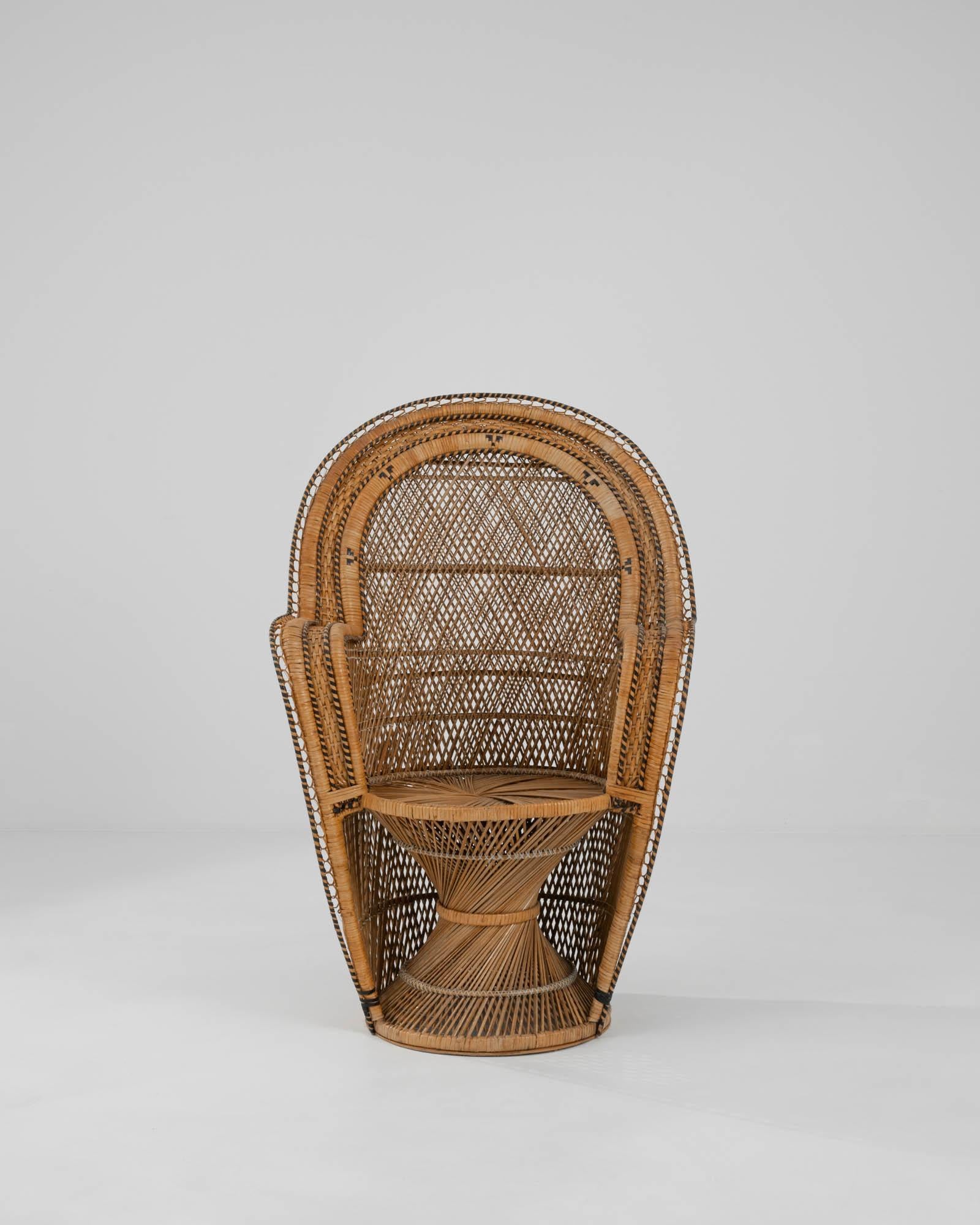 In typical mid-20th century rattan fashion, an “Emmanuelle” style armchair from circa 1960. This throne-like chair has an iconic shape, with black striped ornament and a large oval back. The swirling rattan seat and base grounds the piece while