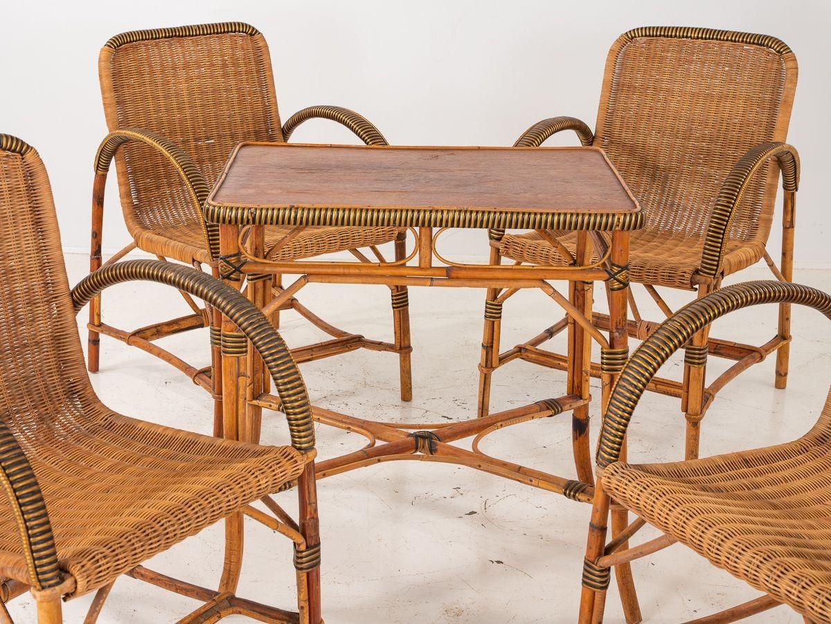 A set of woven wicker or rattan French 1960s armchairs, table, and plant Stand. Each of the four armchairs has a comfortable pitch and seat. The side table and plant Stand feature the same woven design and materials to complete the set. Wear