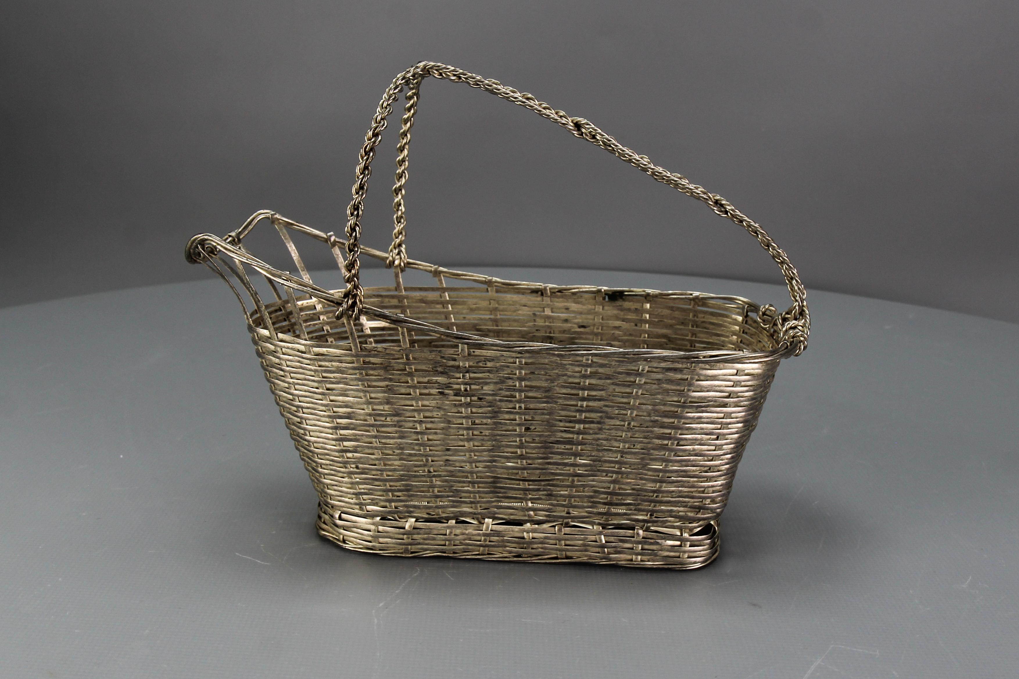 Portabotellas o cesta francesa de metal trenzado de color plateado de hacia la década de 1970.
Dimensiones: altura: unos 18 cm; longitud: unos 22 cm; anchura: 9 cm.
En buen estado, con cierto desgaste propio de la edad y el uso: algunos signos de