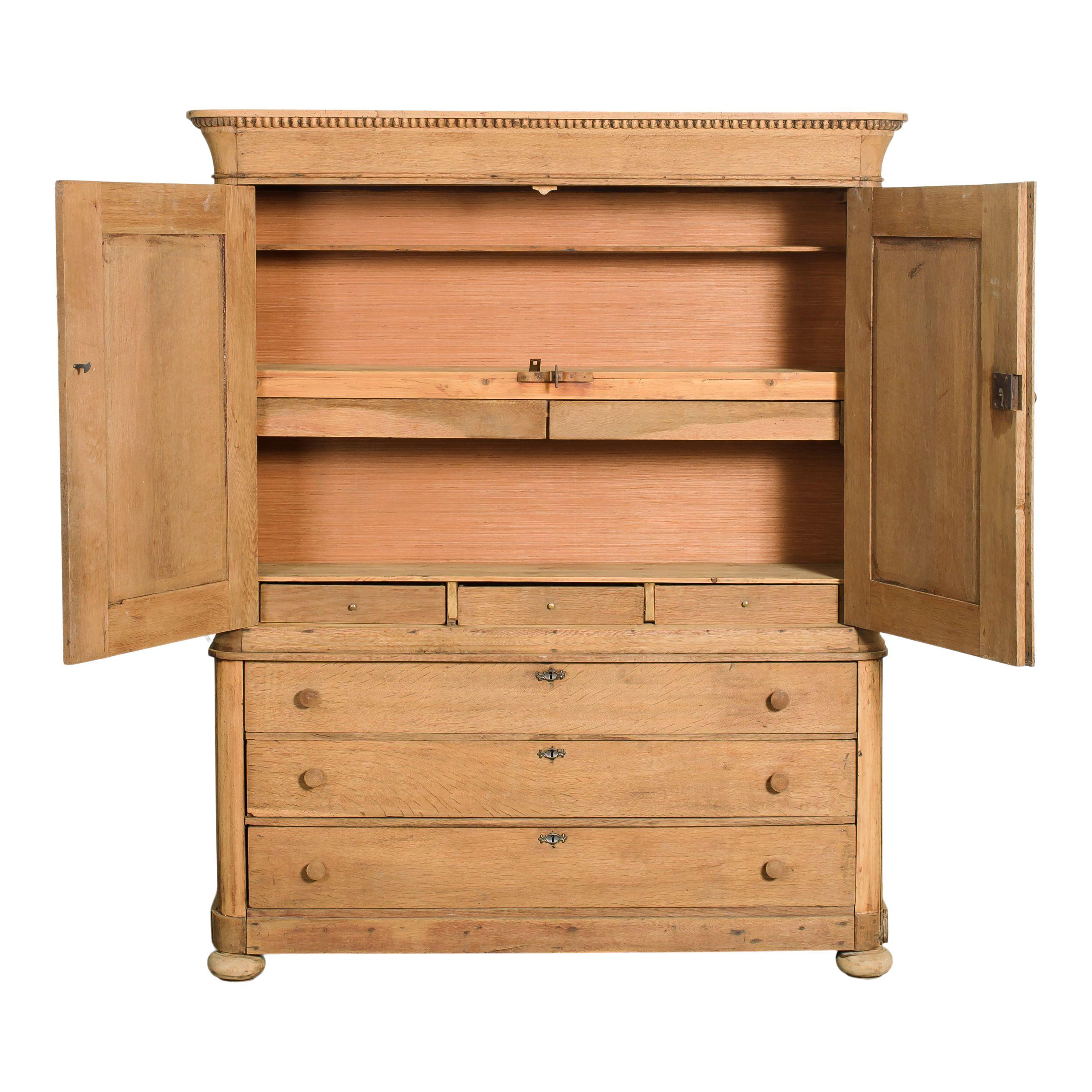 Un armadio vintage in legno chiaro con ripiani e cassetti. Il legno morbido e caldo conferisce un fascino vintage e accogliente a qualsiasi ambiente. Le ante superiori si aprono su scaffali e tre piccoli cassetti, mentre quelle inferiori presentano
