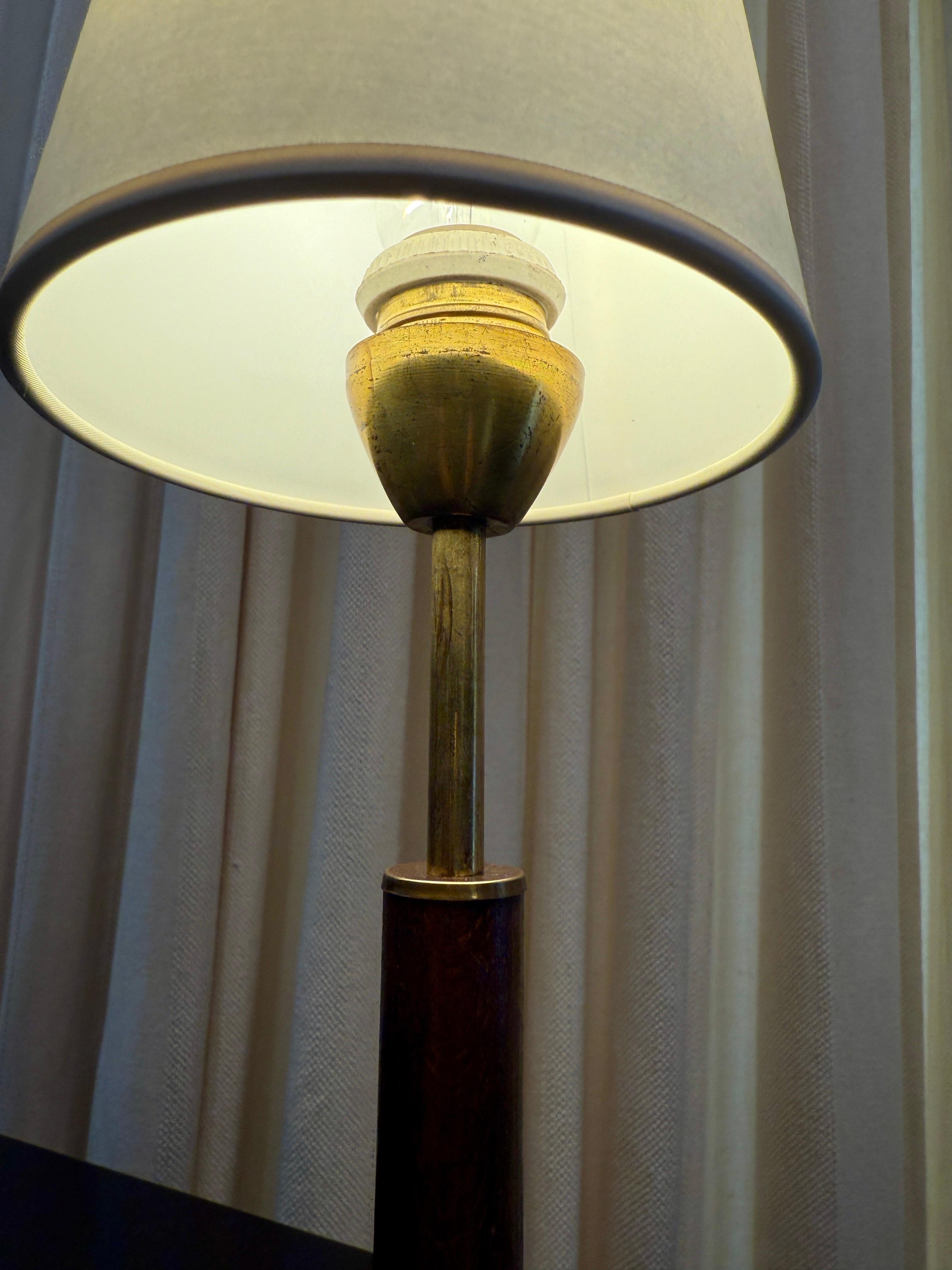 This lovely tri-pod brass petite table lamp features a wood column to central body with original aged patina to brass.  Newly rewired with twisted silk and new plug for US standards.  Paper shade is vintage but is included with the lamp. 