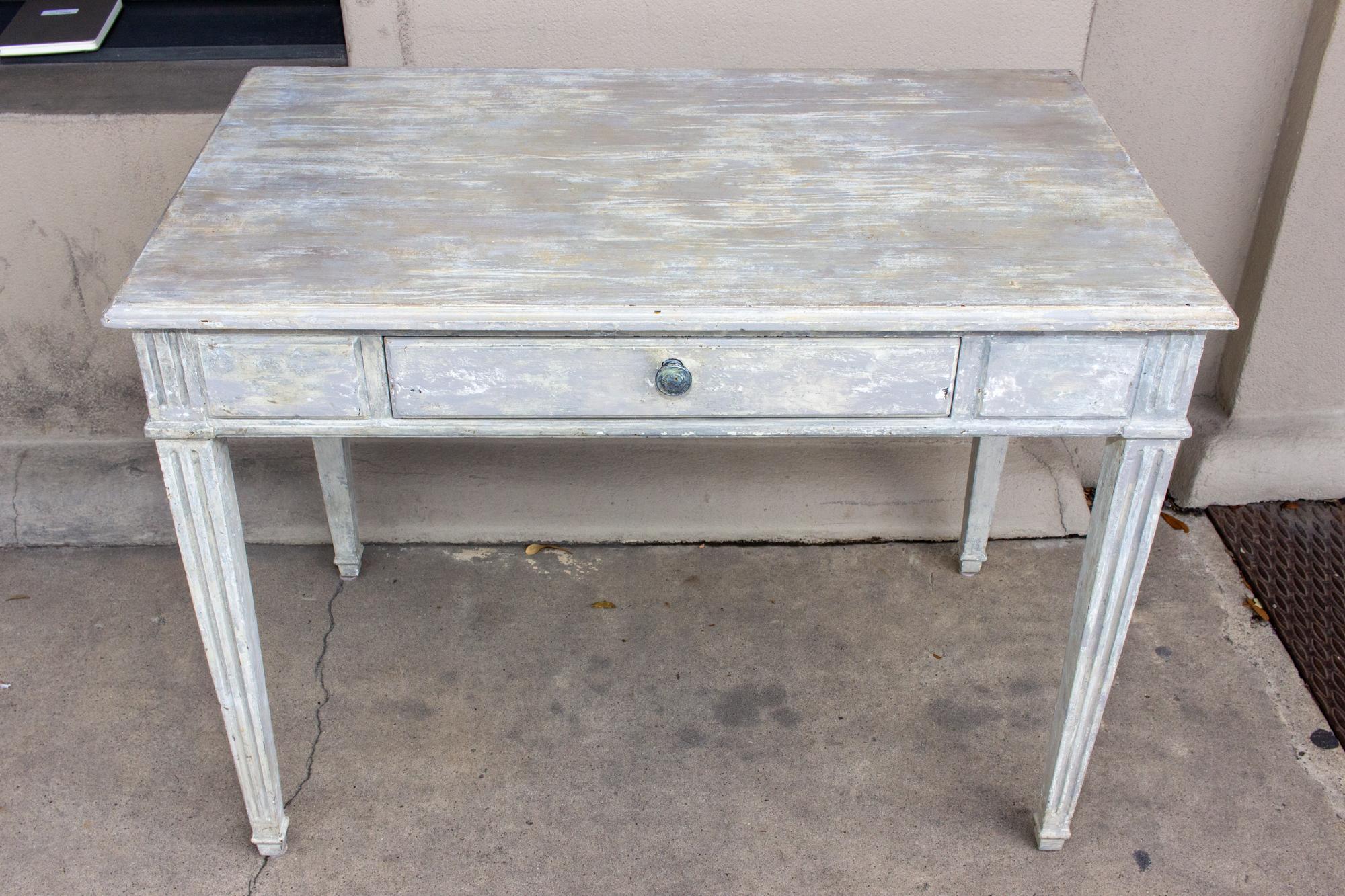 A charming and useful vintage French solid wood desk with a beautifully hand-painted greige finish. There is a single center drawer at front with generous storage space and a simple round pull. The legs are tapered with fluted details that continue