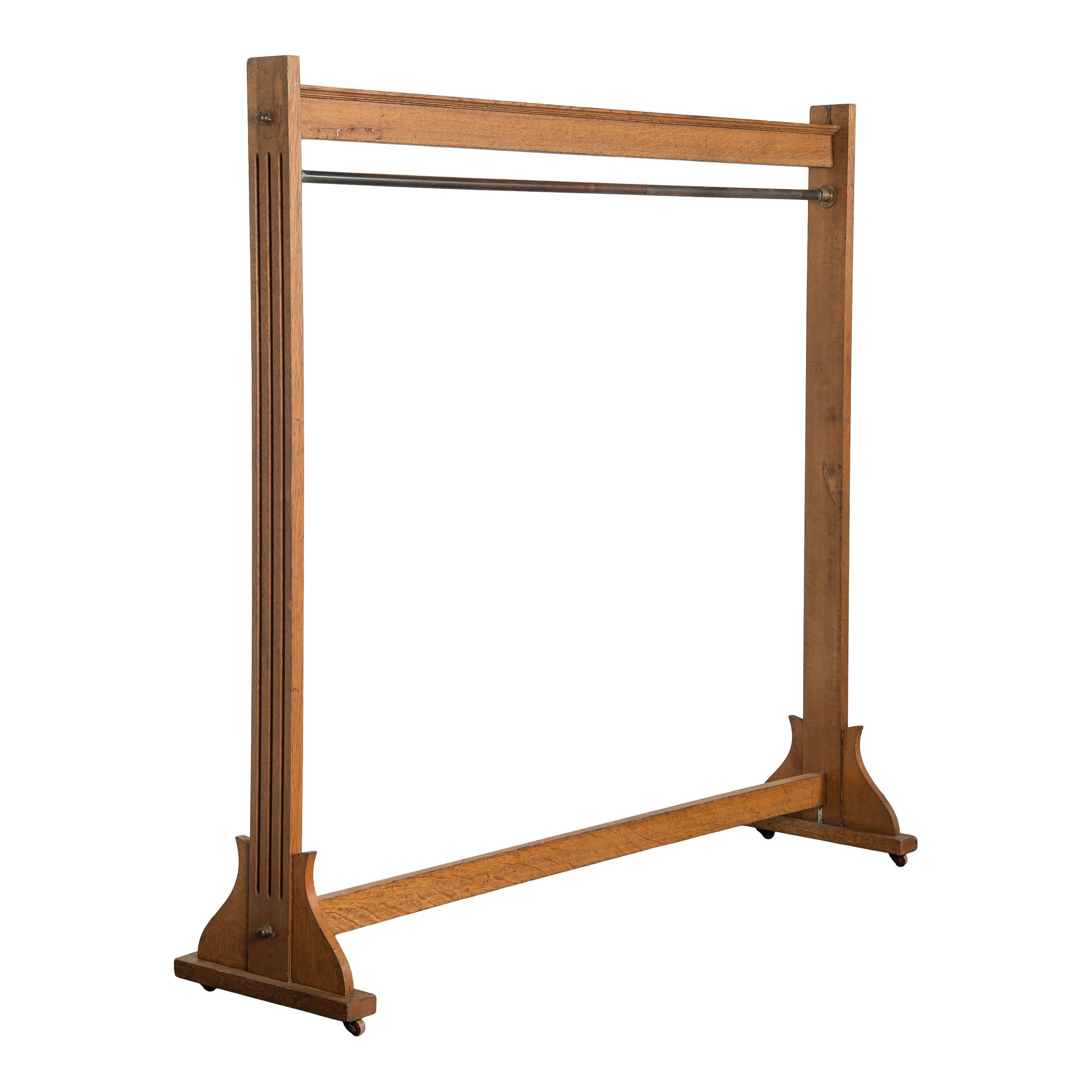 A simple vintage wood clothing rack with small metal wheels from France and made in the 20th century. This simplicity of this clothing rack is very timeless, with elegant and classic carved details in the wood on the sides. The bar for hanging